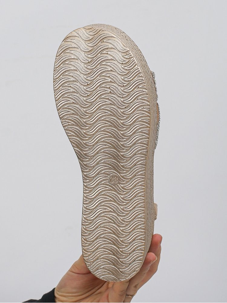 Sole view of hotfix rhinestone sandals with textured grip pattern held by hand