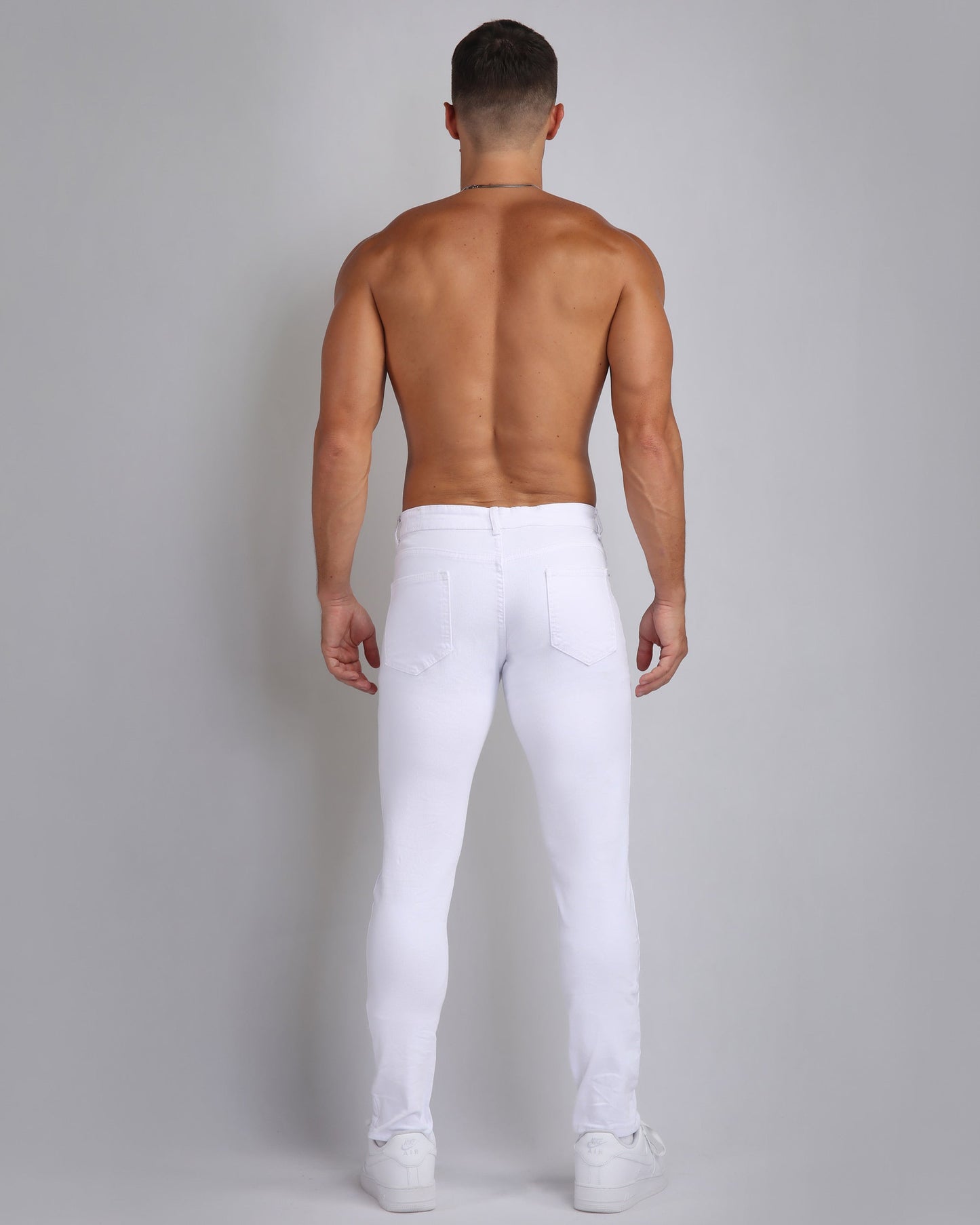 Back view of a man wearing irregular ripped white jeans for a trendy casual look