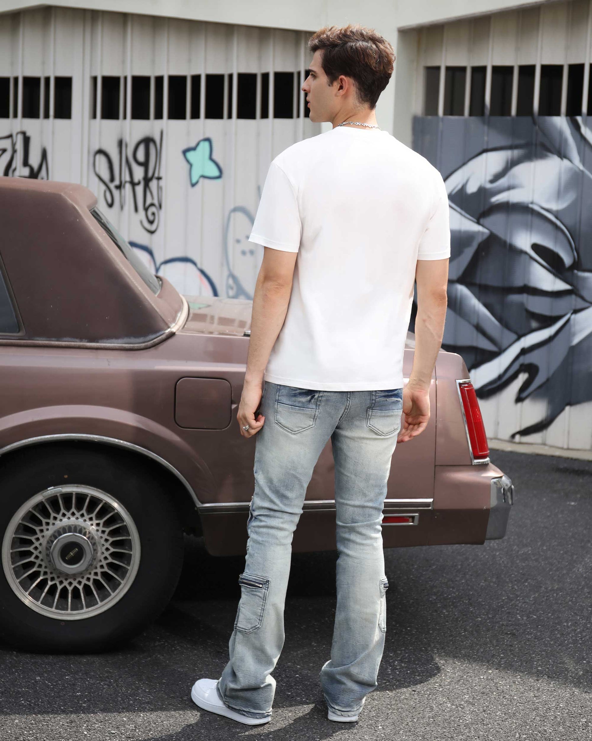 Logeqi light wash distressed cargo jeans styled with a white t-shirt against a vintage car backdrop