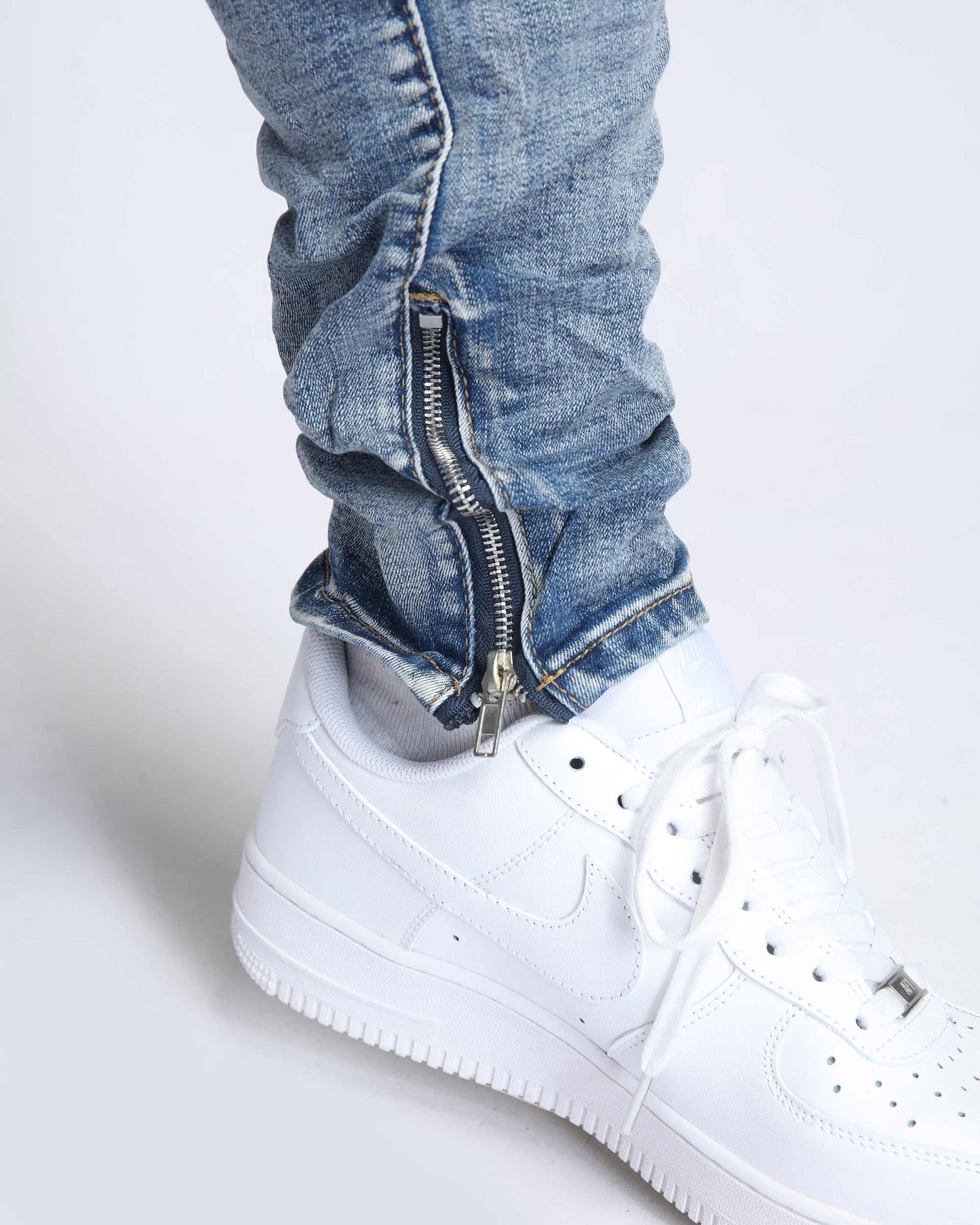 Logeqi light wash ripped jeans with stylish zip details paired with white Nike sneakers