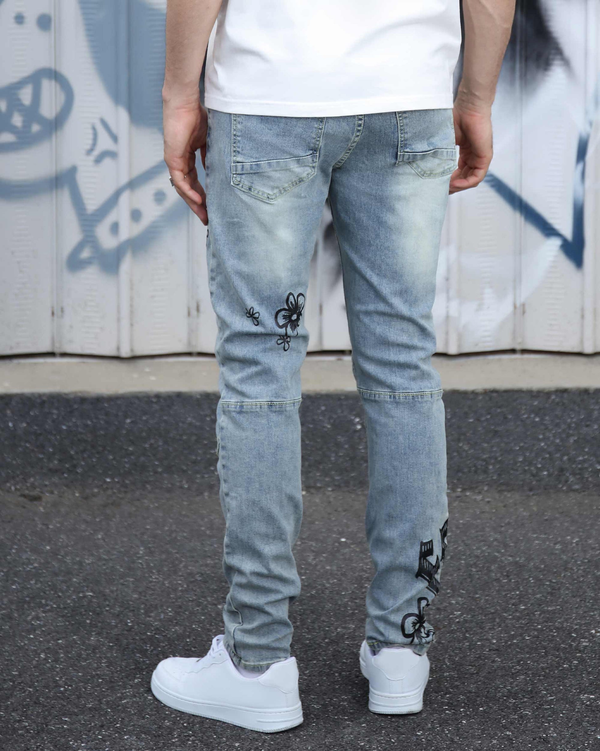 Logeqi light wash street art jeans with black graphic designs worn with white sneakers