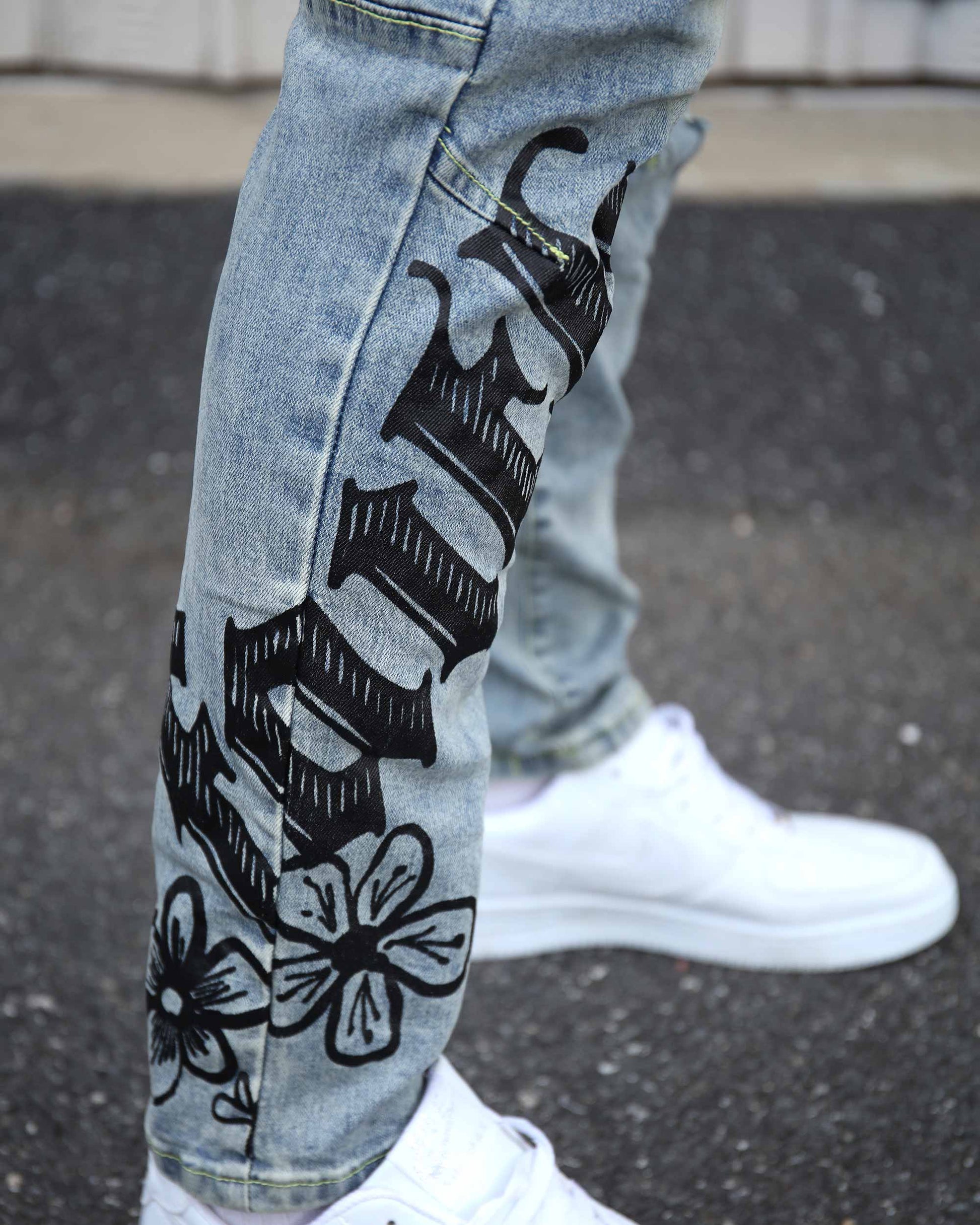 Logeqi light wash street art jeans with black graphic floral and text design on leg