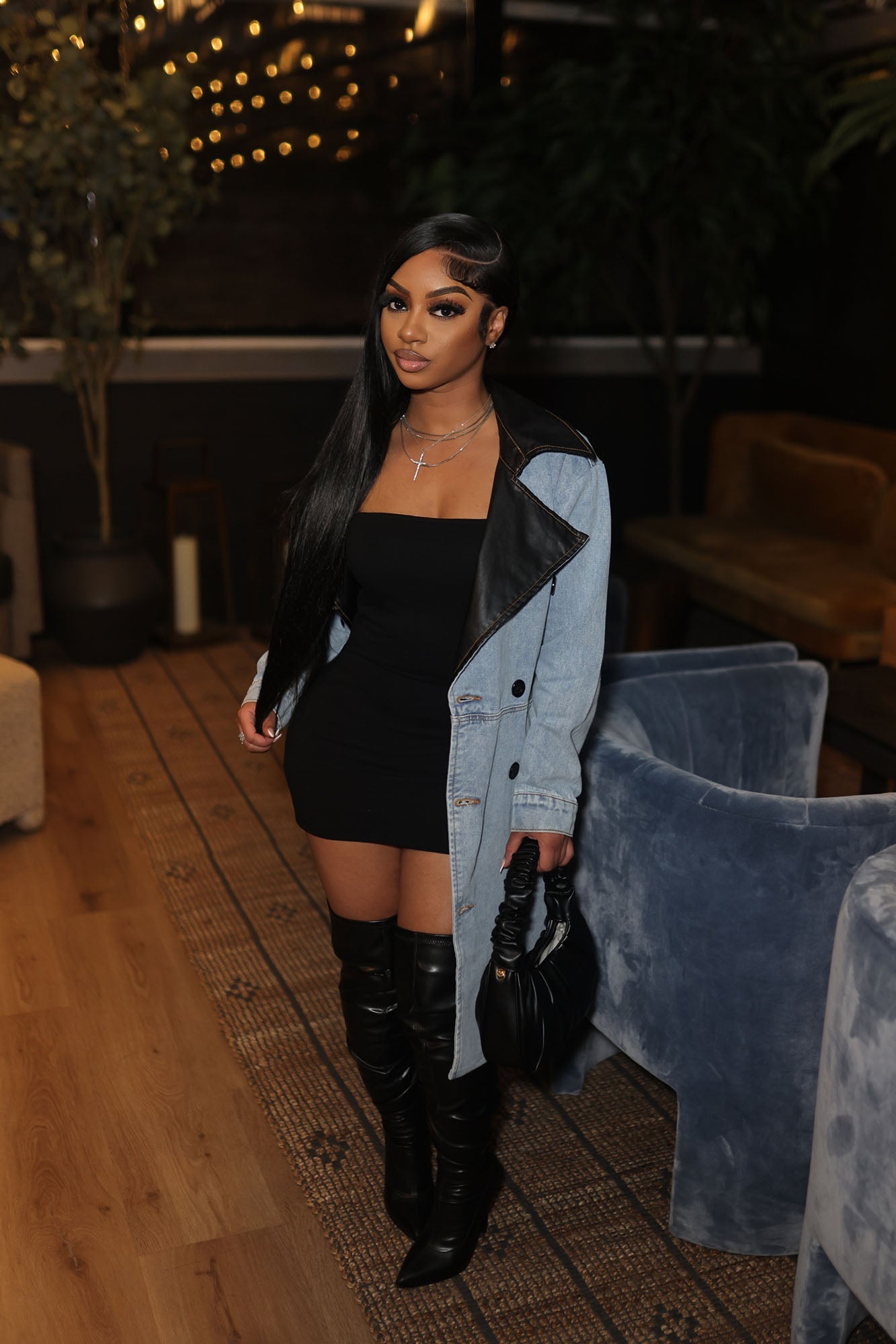 Fashion Nova light wash trench coat for women styled over a black mini dress and knee-high boots