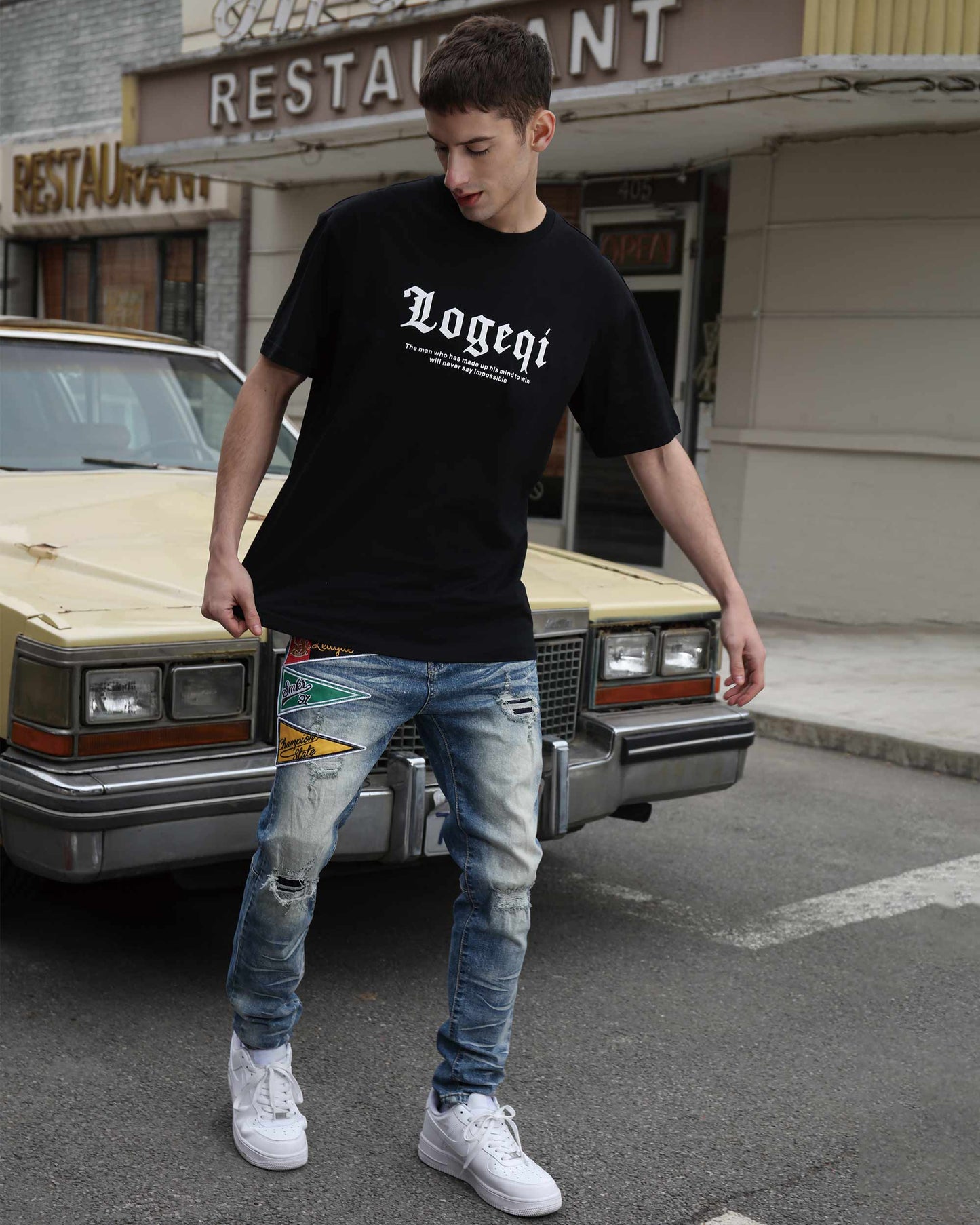 Man wearing Logeqi medium wash distressed jeans paired with a black t-shirt and white sneakers