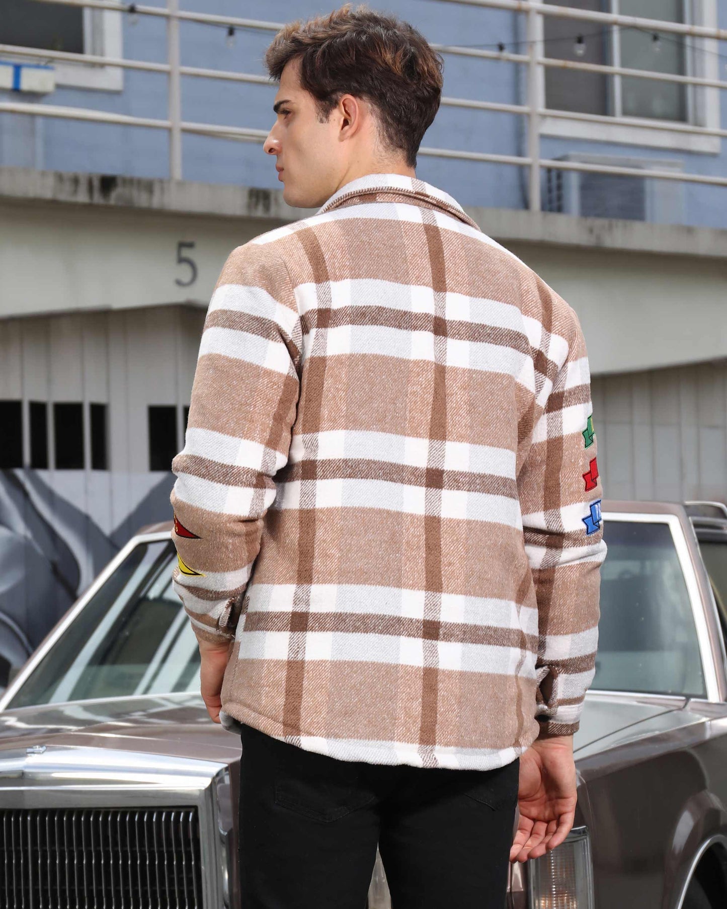 Back view of man wearing Logeqi modern plaid moto jacket in beige and white with colorful patches on sleeve
