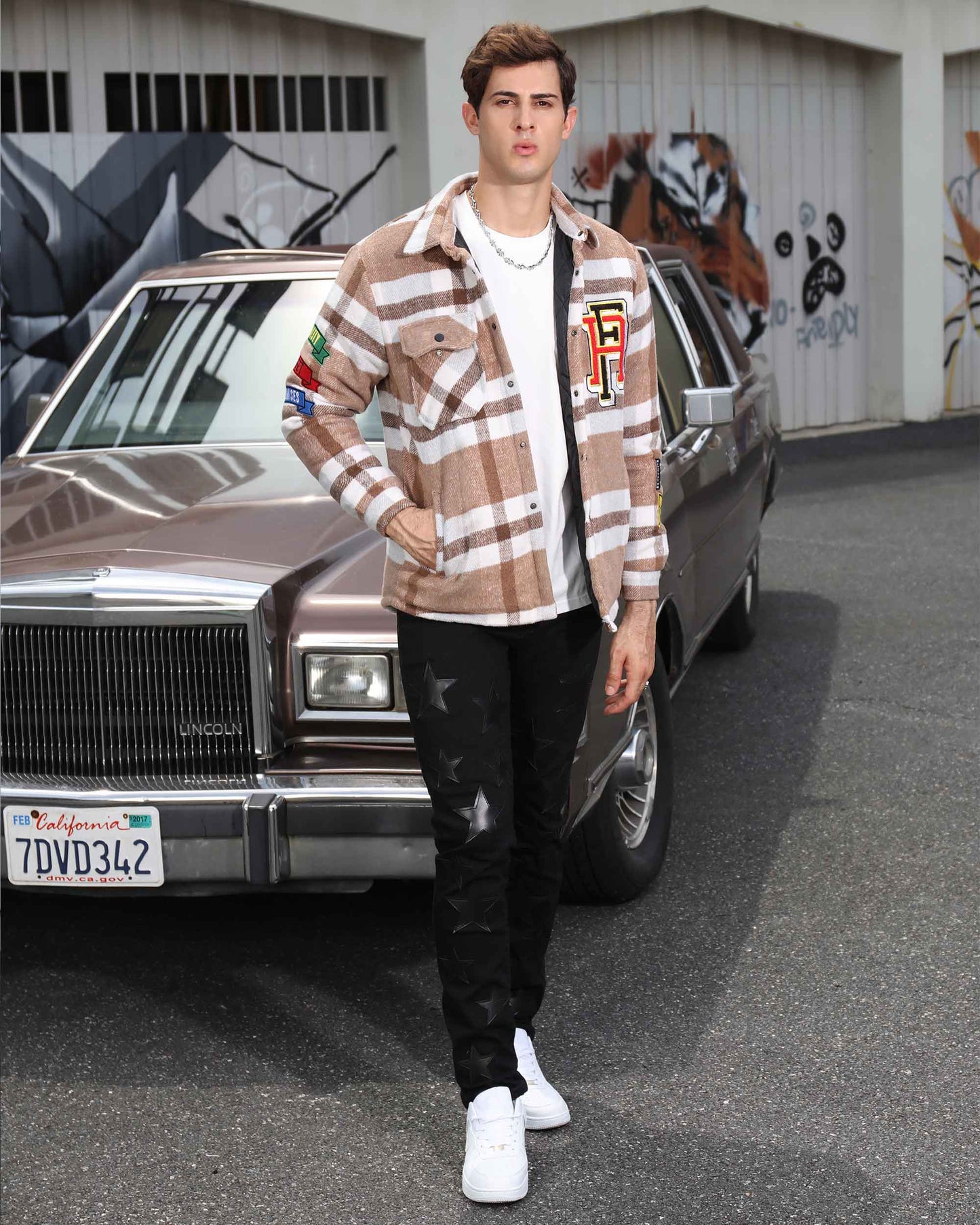 Man wearing Logeqi modern plaid moto jacket walking in front of a vintage car with graffiti background