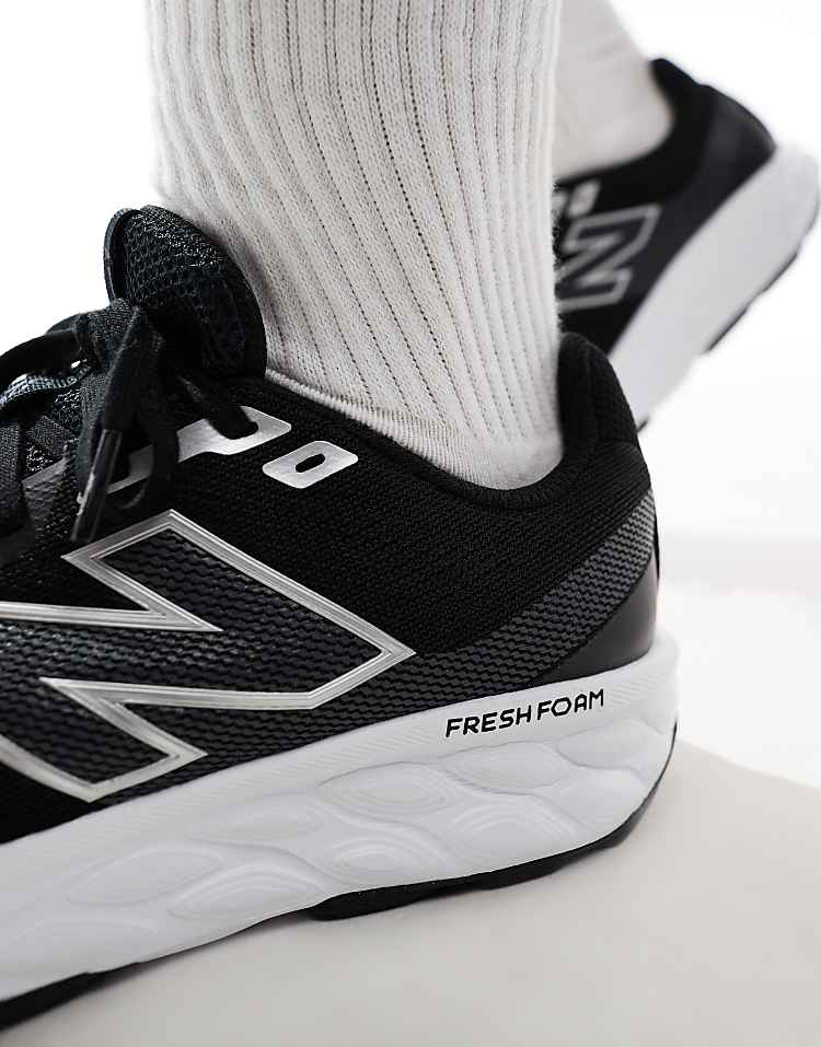 Close-up of New Balance 520 running shoes in black with white Fresh Foam sole worn with white socks