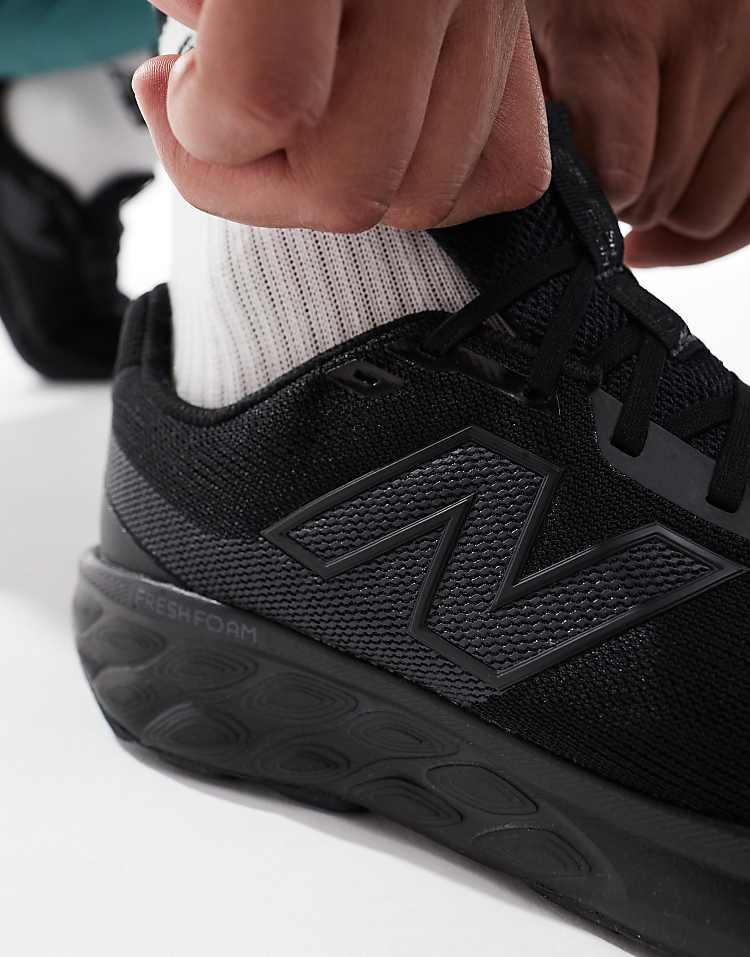 Black New Balance 520 running shoes being tied on foot with white sock for men