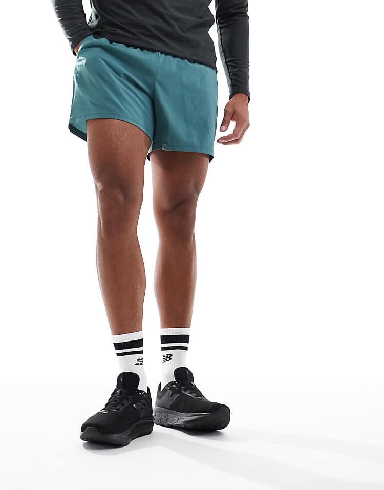 Man wearing black New Balance 520 running shoes with white athletic socks and teal shorts