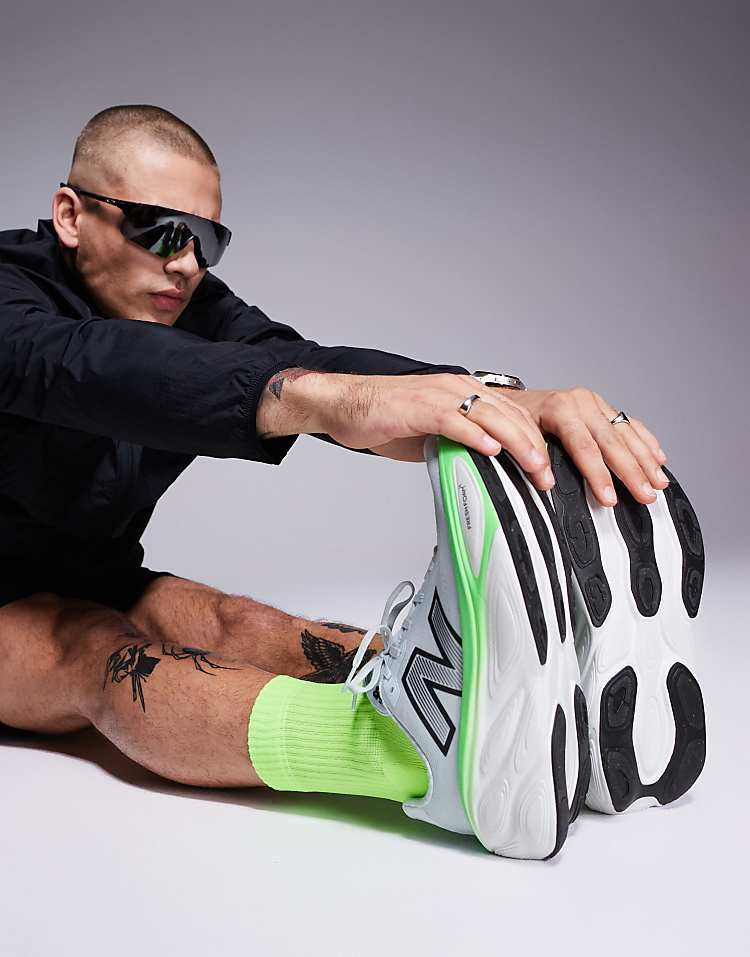 Man stretching wearing New Balance running shoes with neon green socks in sporty black outfit