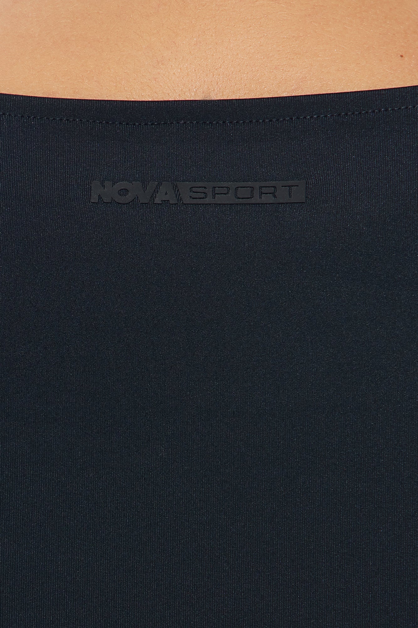 Close-up of Nova Sport black active crop top for women with logo detail on neckline