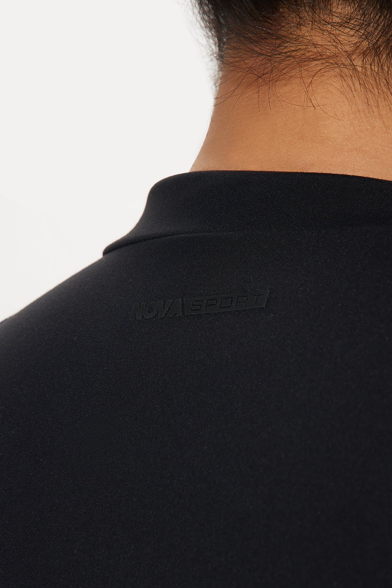 Close-up of Nova Sport logo on the back of a black active jumpsuit for women