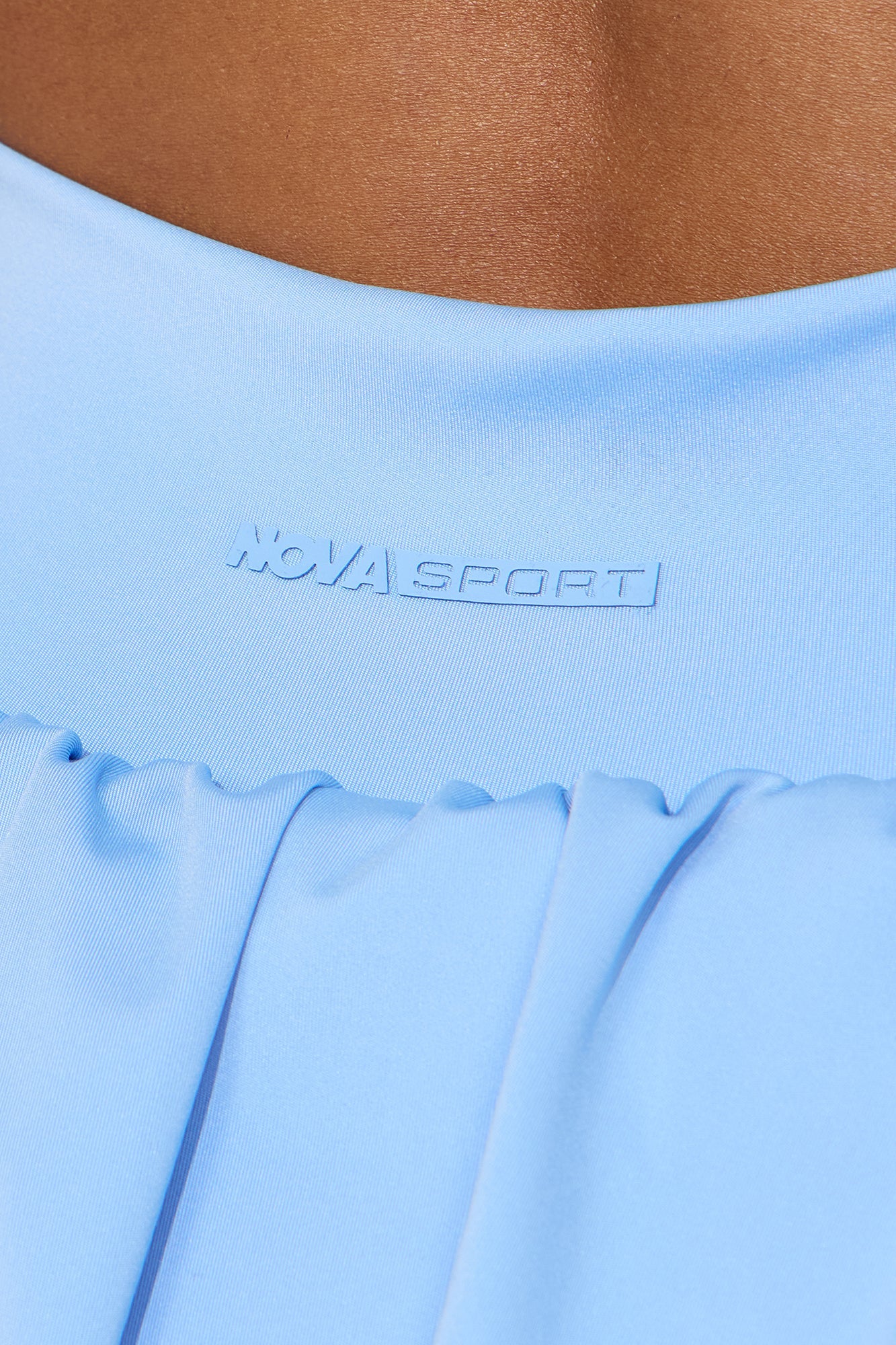 Detail of Nova Sport logo on a light blue bubble skirt showing soft fabric and stylish design