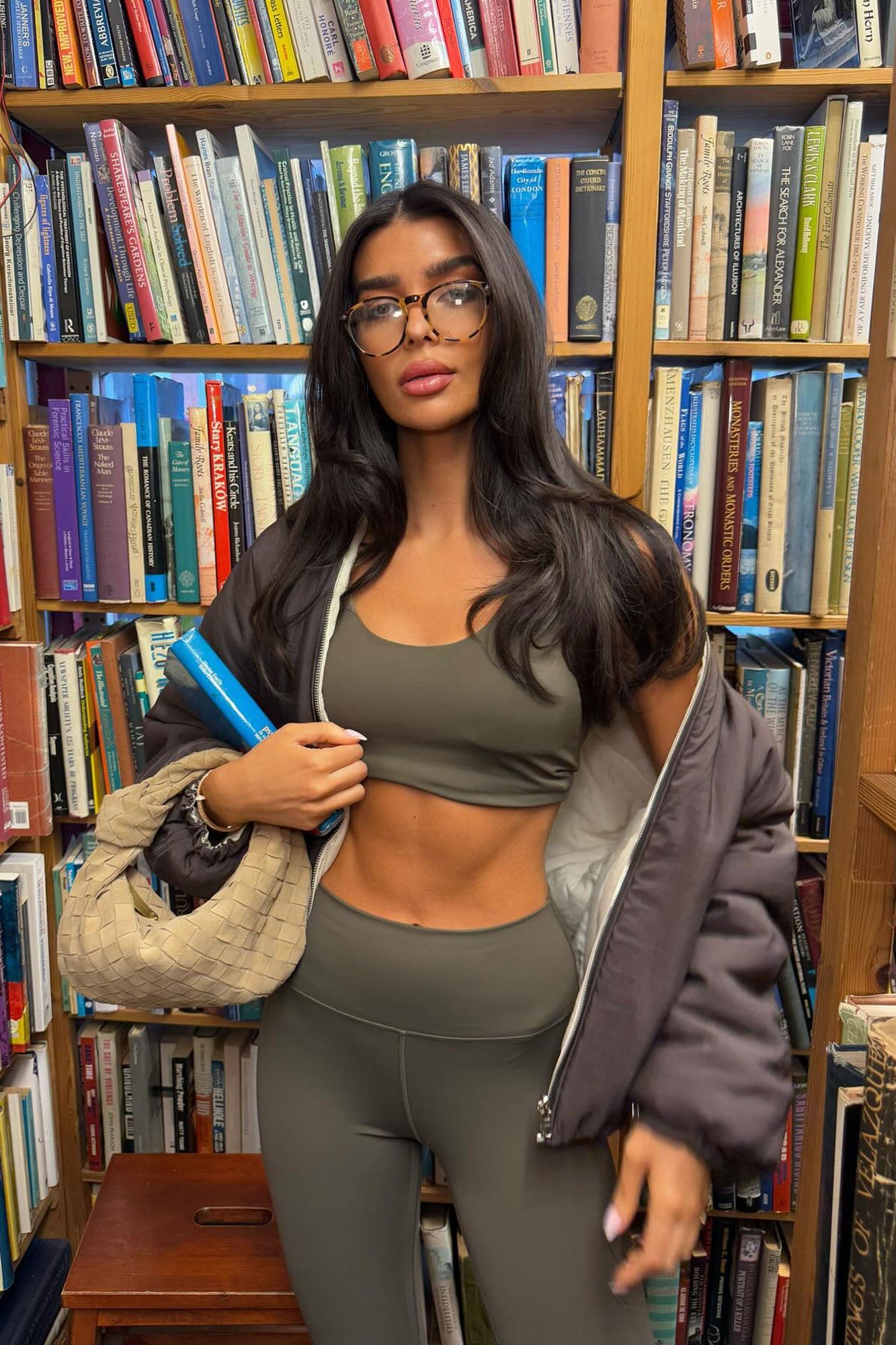 Fashion Nova olive active jacket for women paired with matching workout attire in a library setting