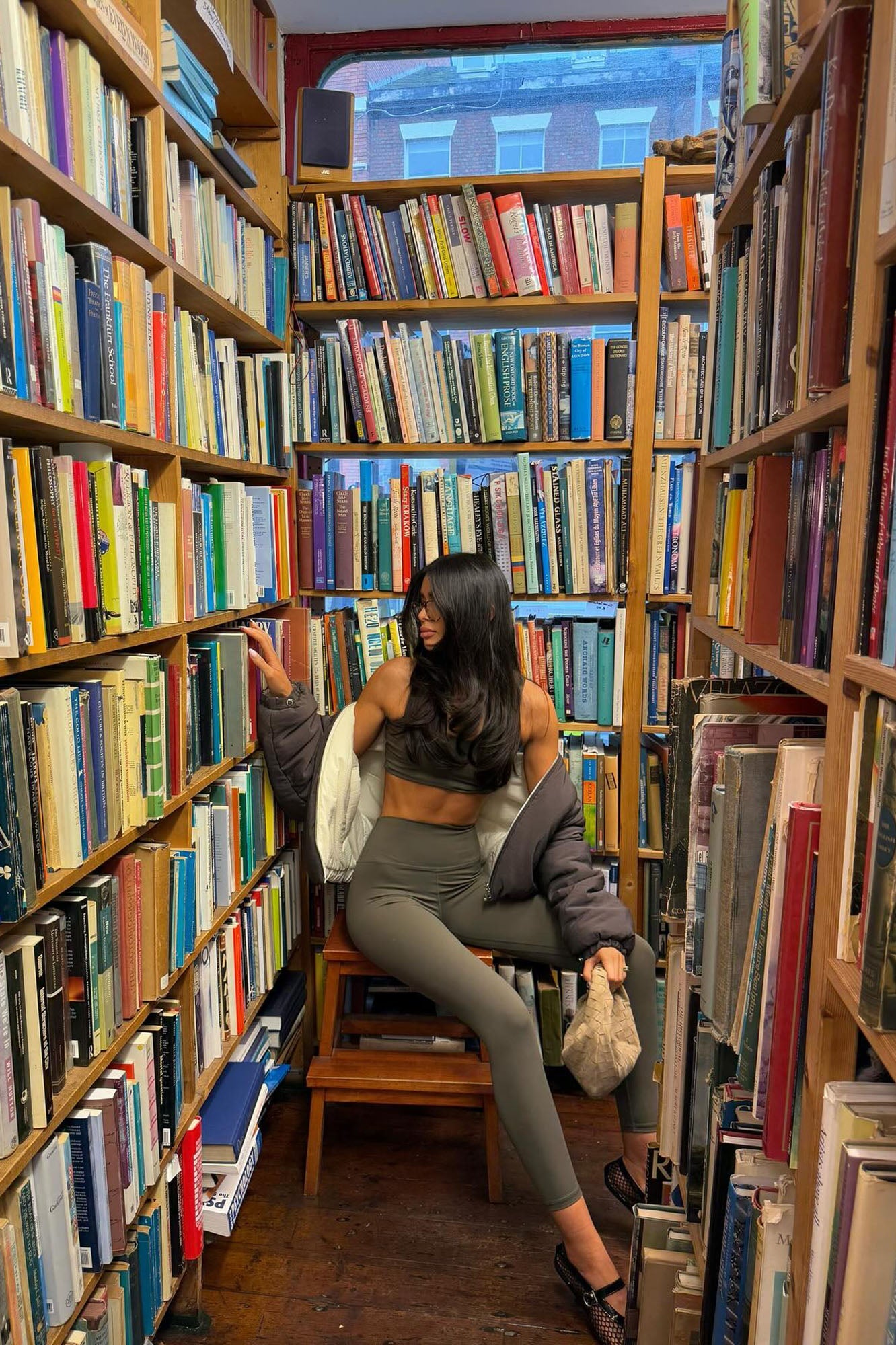 Fashion Nova olive active leggings for women styled with a cropped top in a cozy library setting