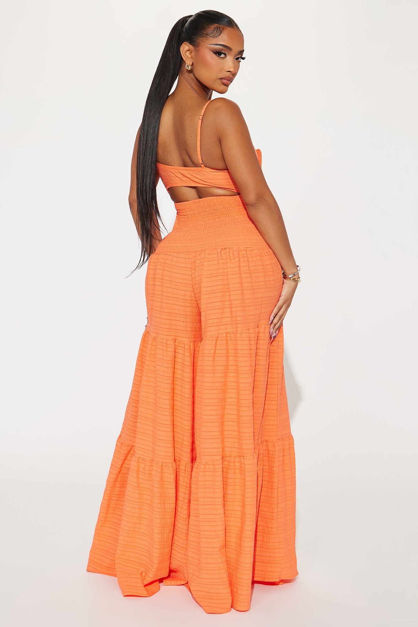 Back view of an orange jumpsuit for women with a tiered design from Fashion Nova