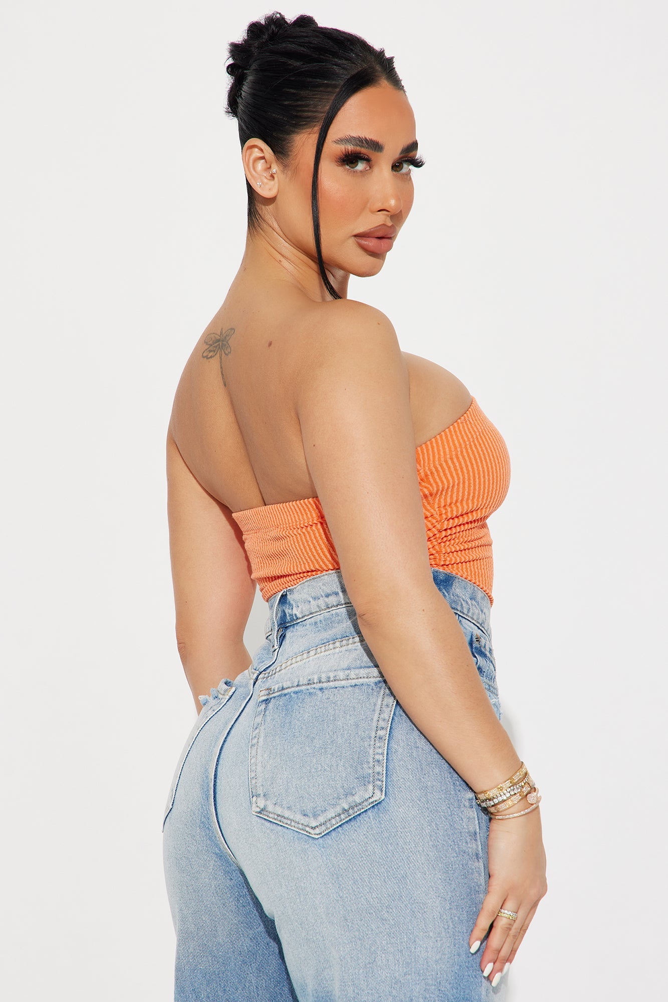 Model wearing an orange ribbed bodysuit paired with high-waisted jeans for a stylish look