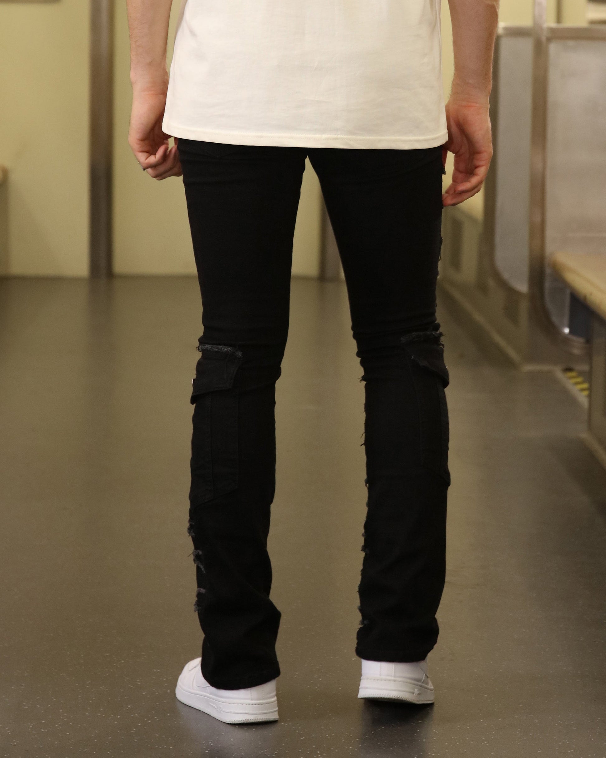 Back view of Logeqi raw edge black jeans worn with white sneakers and a white shirt