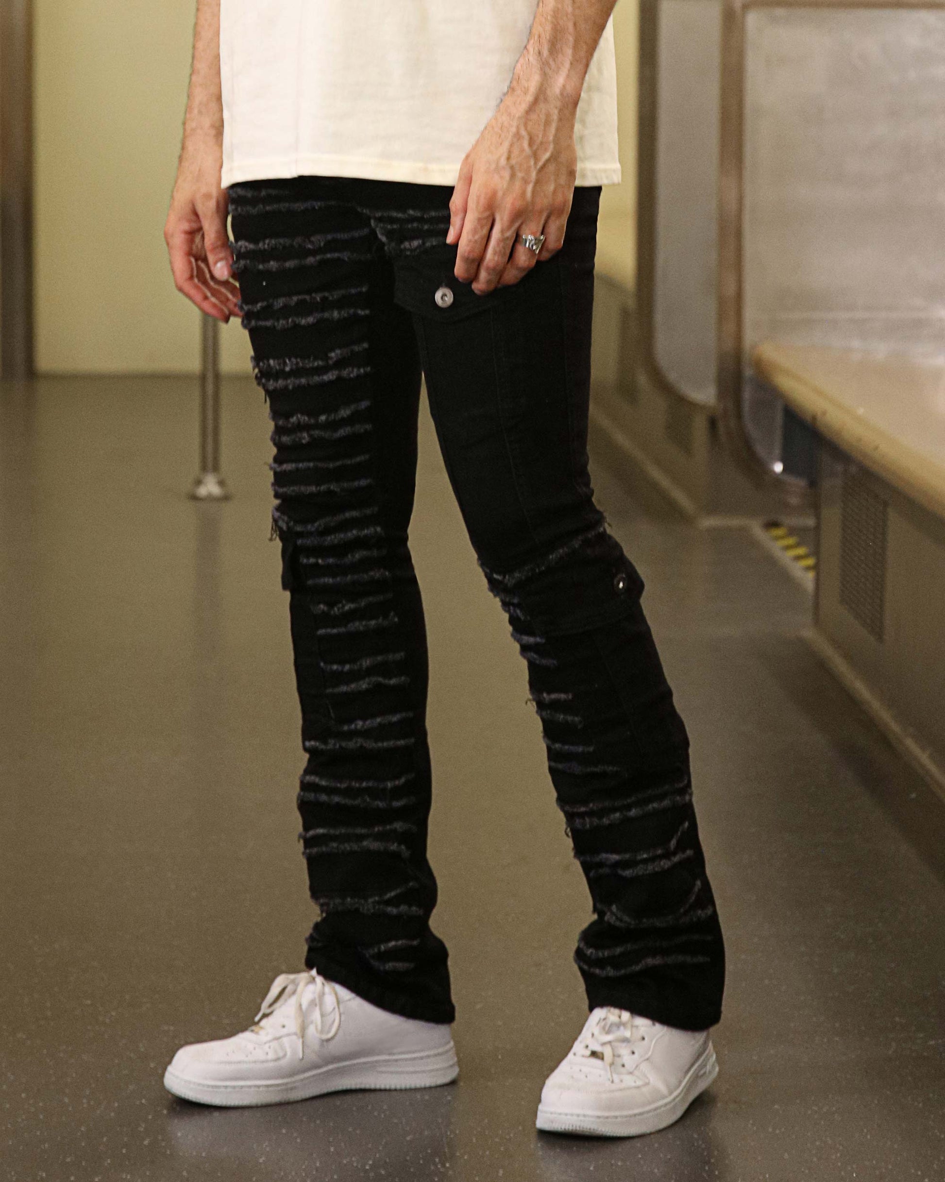 Logeqi raw edge black jeans featuring distressed texture and button details paired with white sneakers