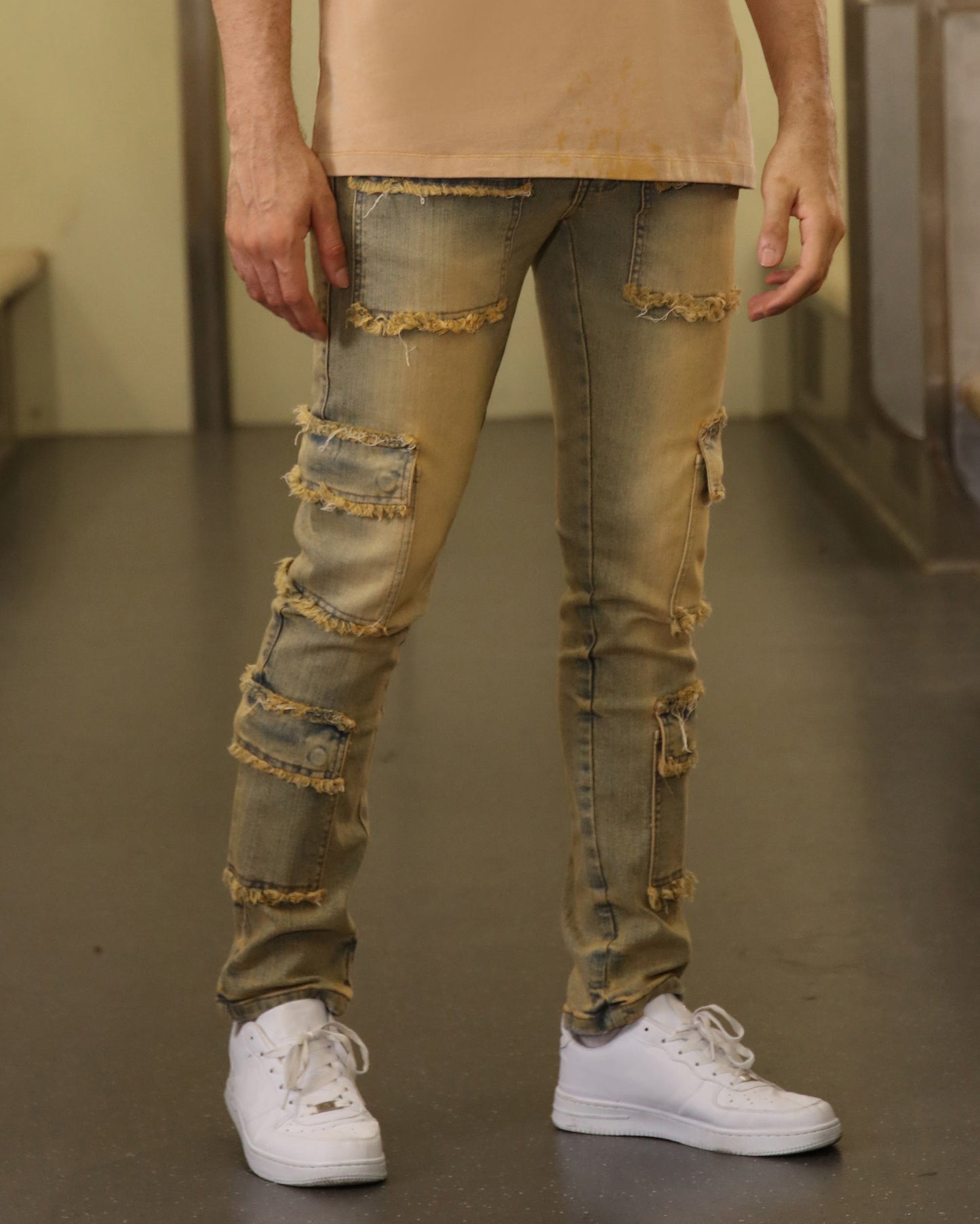 Logeqi raw edge brown jeans with distressed patches and frayed hems worn with white sneakers