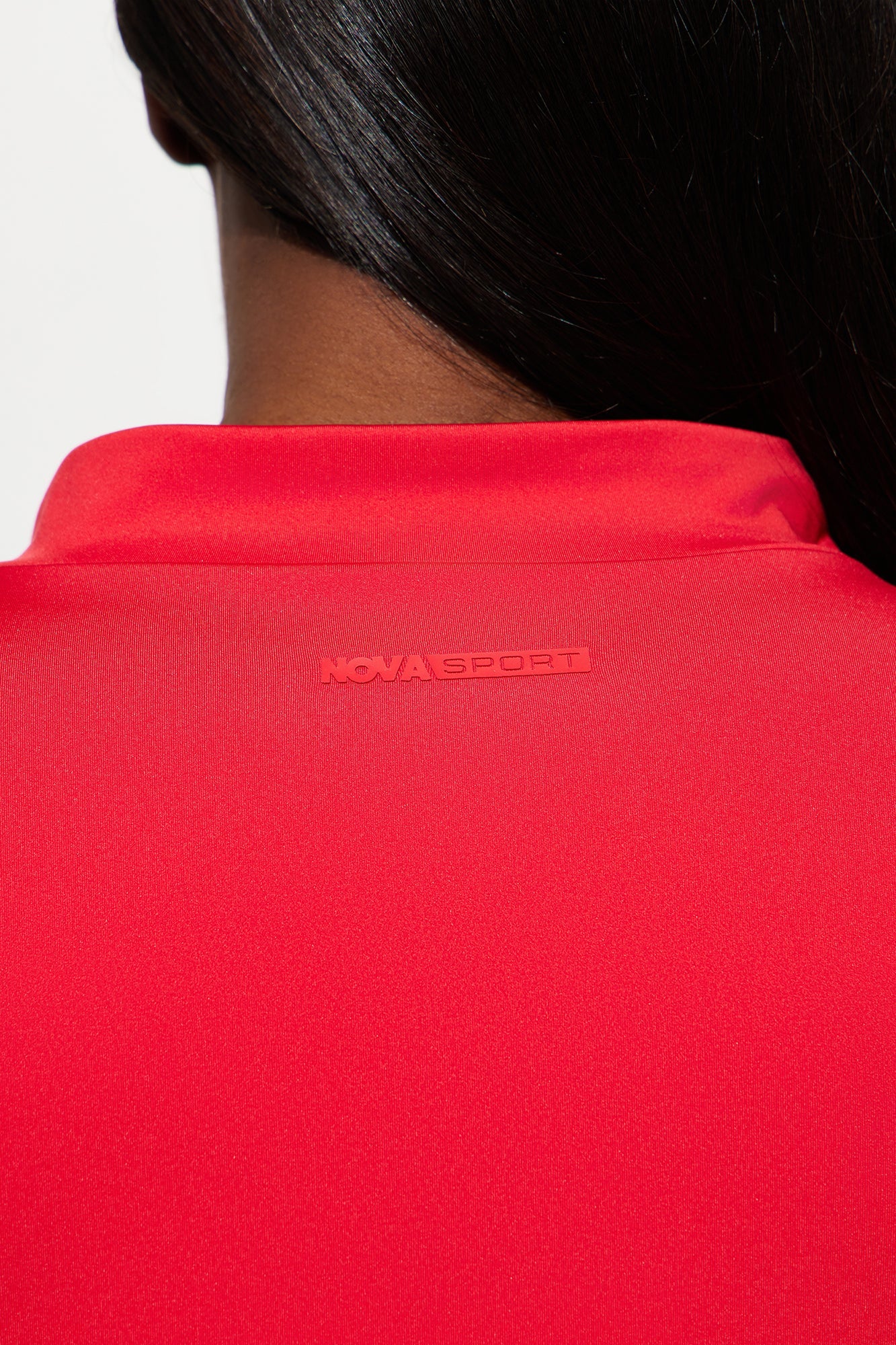 Close-up of Nova Sport red activewear set for women showcasing the logo detail on the collar