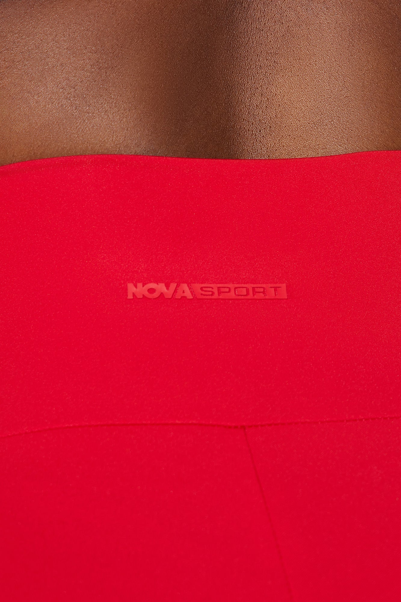 Close-up of Nova Sport logo on the red activewear set for women highlighting premium fabric and design