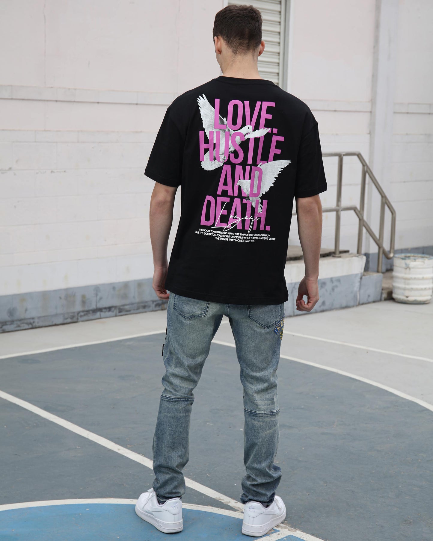 Logeqi ripped patchwork jeans styled with a black graphic t-shirt on a basketball court