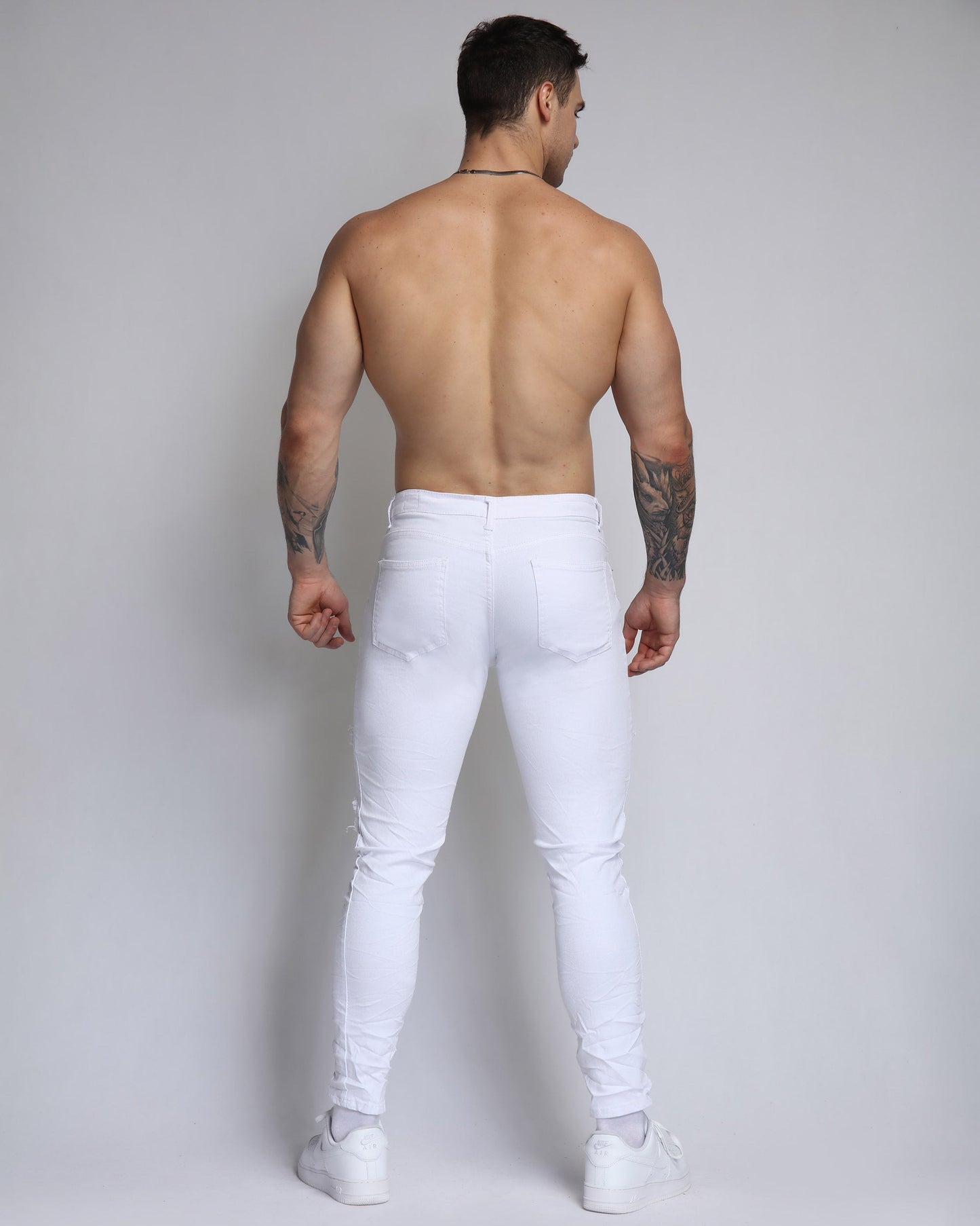 Logeqi ripped white jeans with patches showcased on a male model from the back
