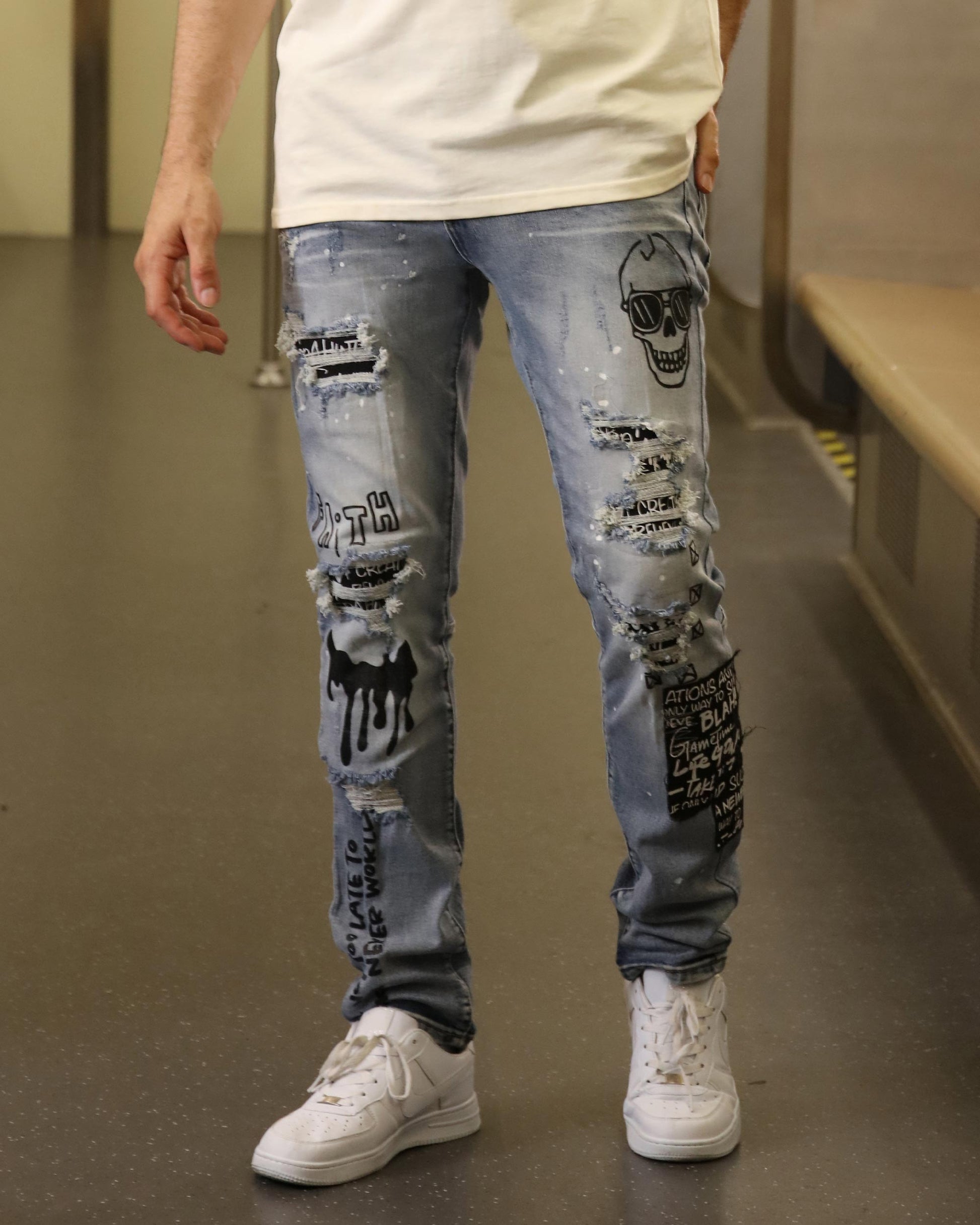 Logeqi skull graffiti ripped jeans in light blue with black skull and text designs on front