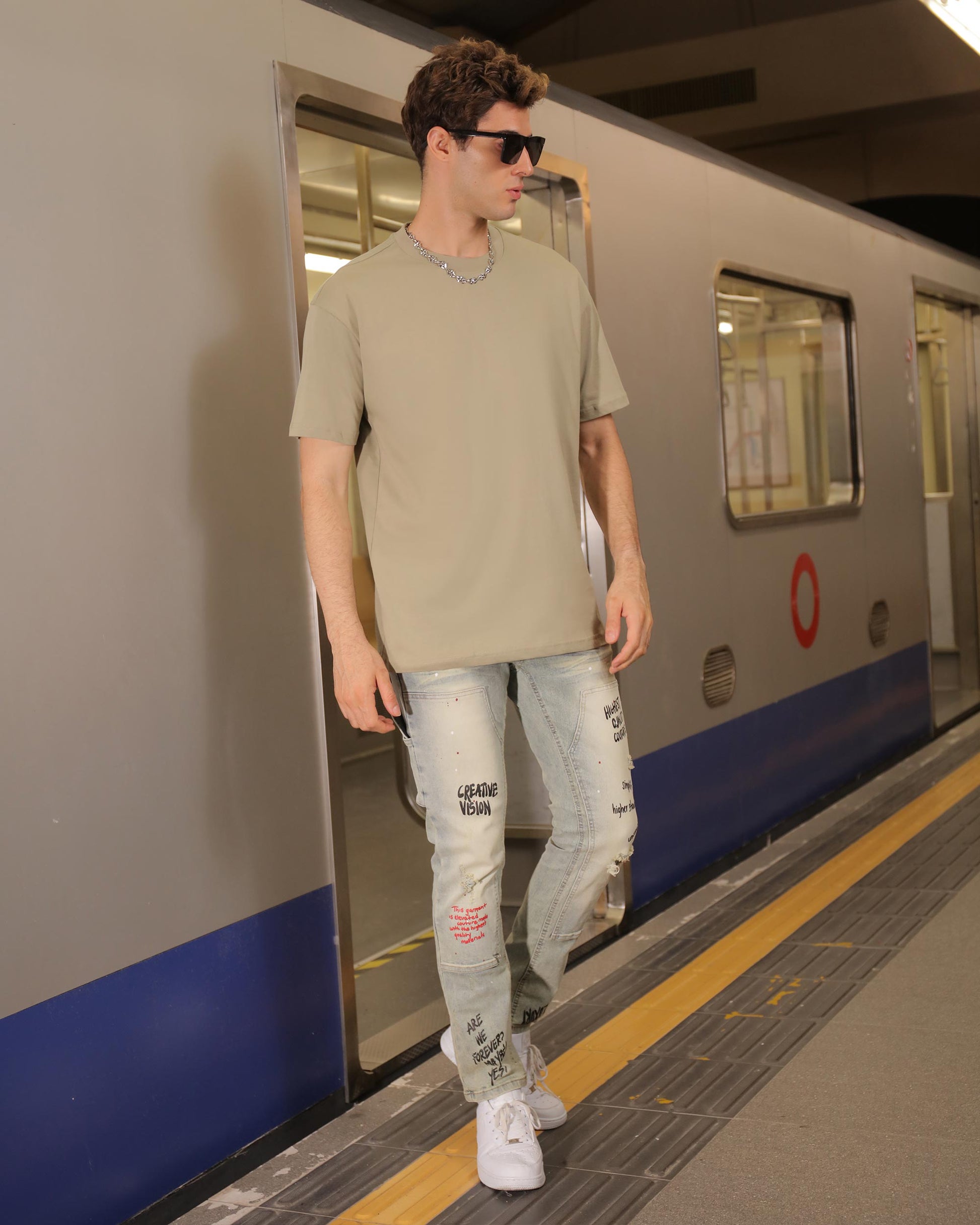Logeqi spray paint graffiti jeans worn by male model standing at subway platform