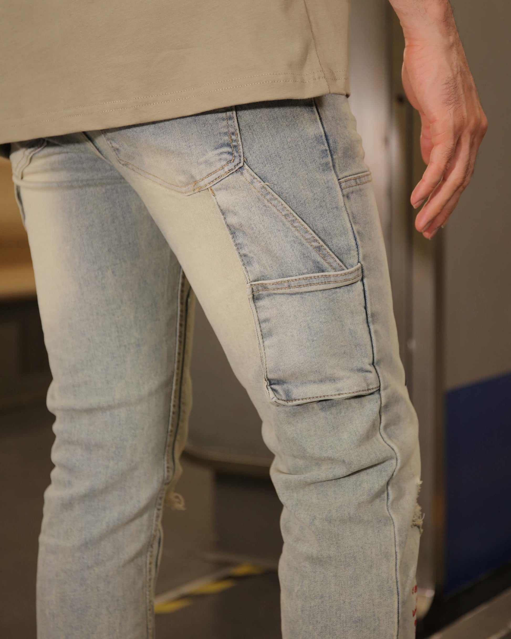 Close-up of Logeqi spray paint graffiti jeans with side pocket detail in light wash denim