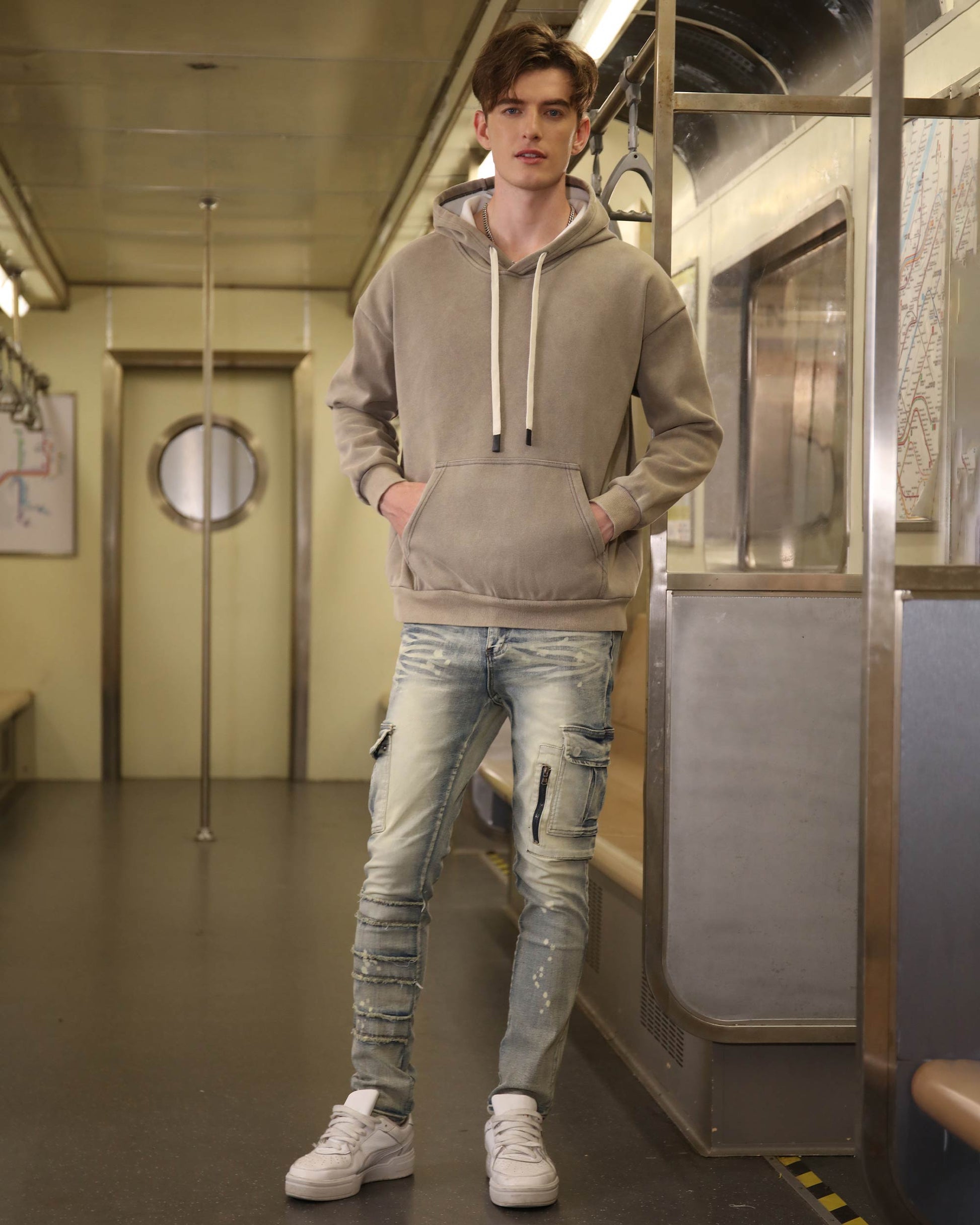 Logeqi spray painted blue cargo jeans worn by male model with hoodie and white sneakers