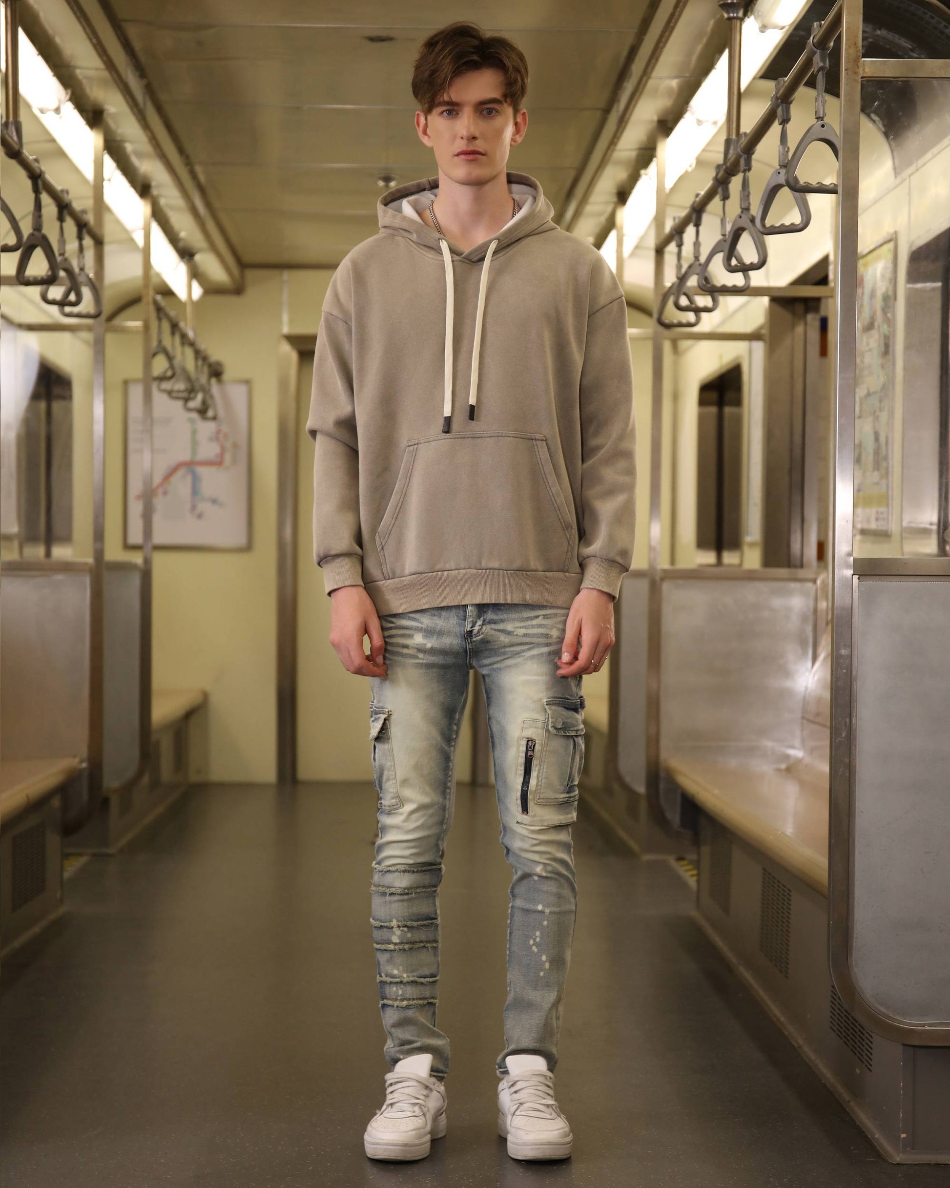 Logeqi spray painted blue cargo jeans worn by model paired with beige hoodie and white sneakers