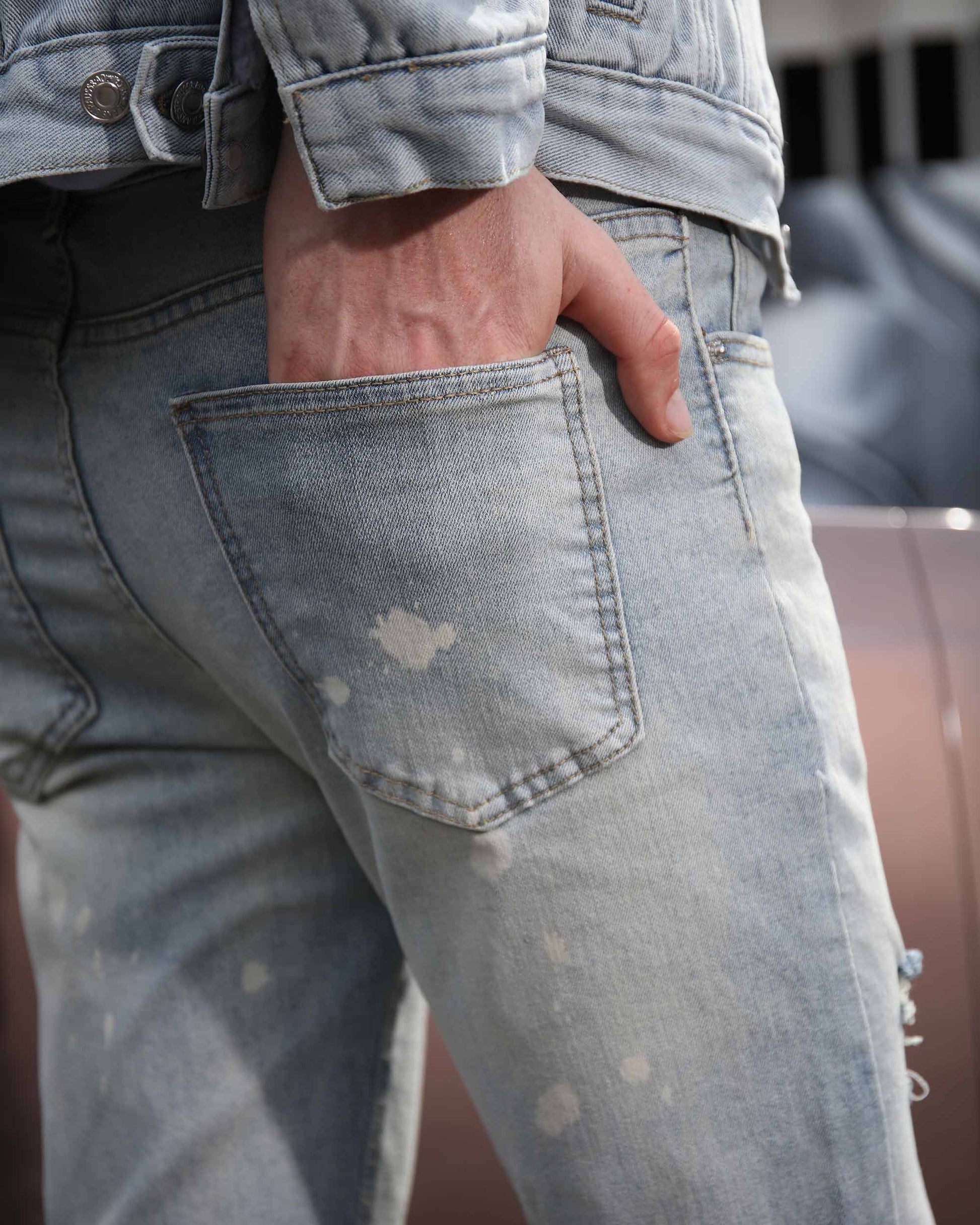 Logeqi spray painted light blue ripped jeans close-up showing back pocket and hand in pocket
