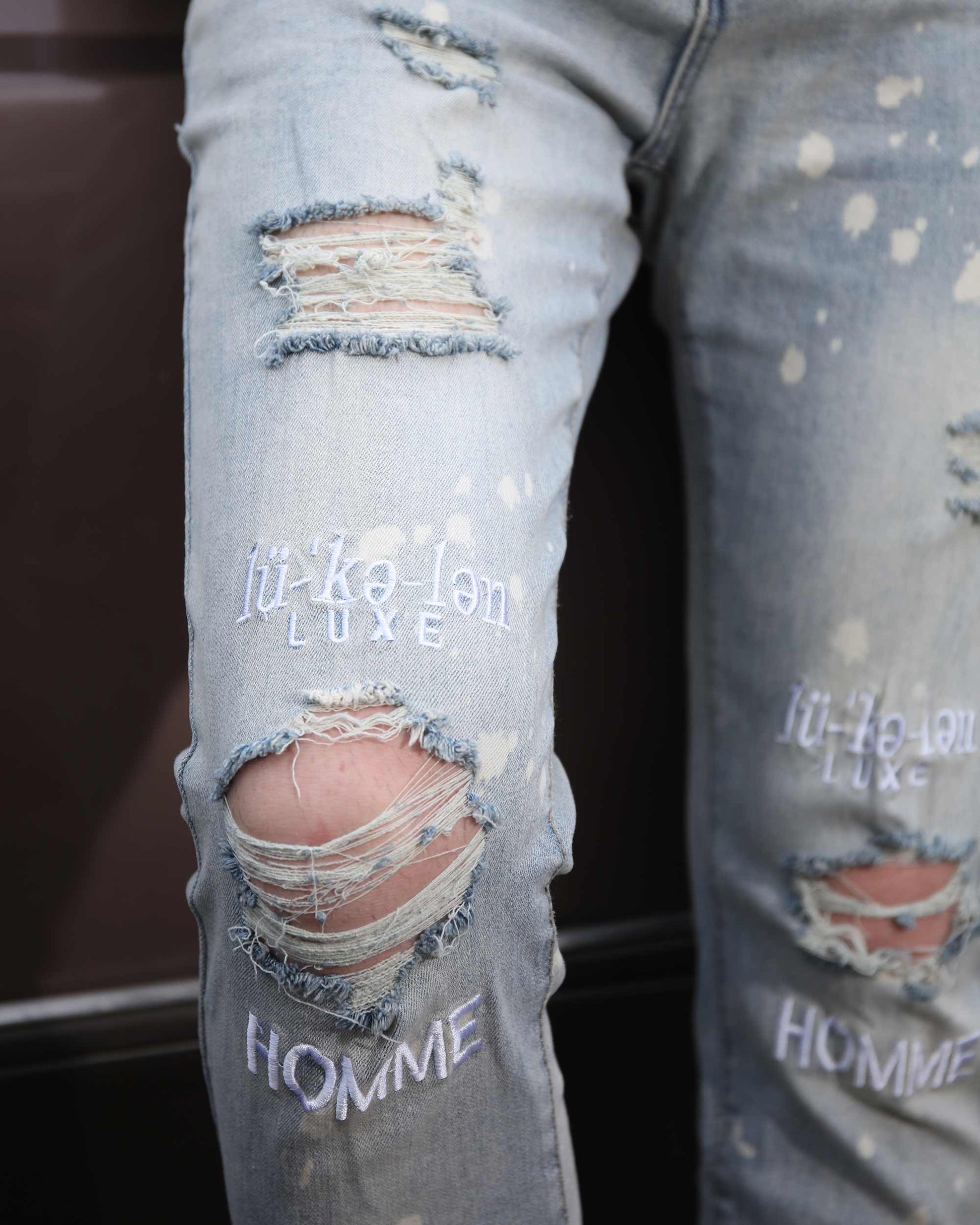 Logeqi spray painted light blue ripped jeans with distressed patches and embroidered details