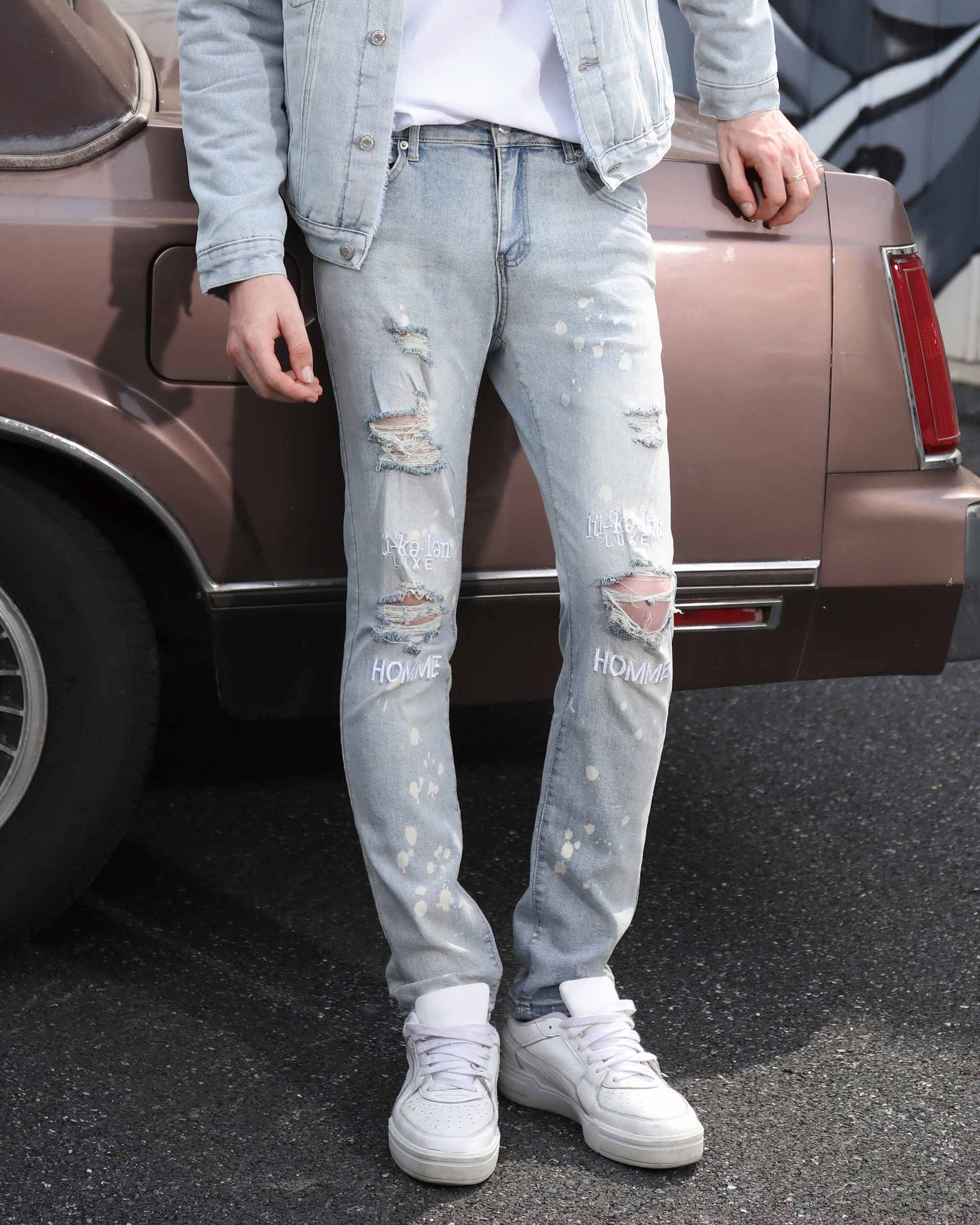 Logeqi spray painted light blue ripped jeans with distressed details worn with white sneakers