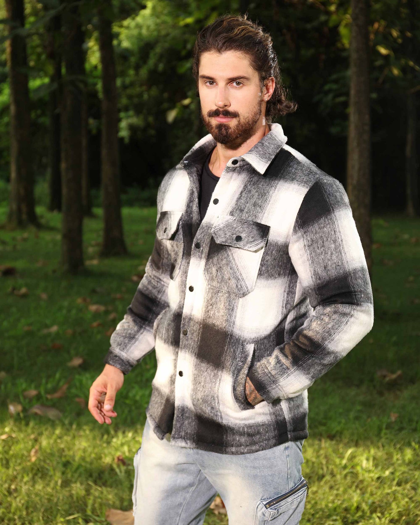 Man wearing a black and white spring plaid jacket by Logeqi outdoors in a forest setting