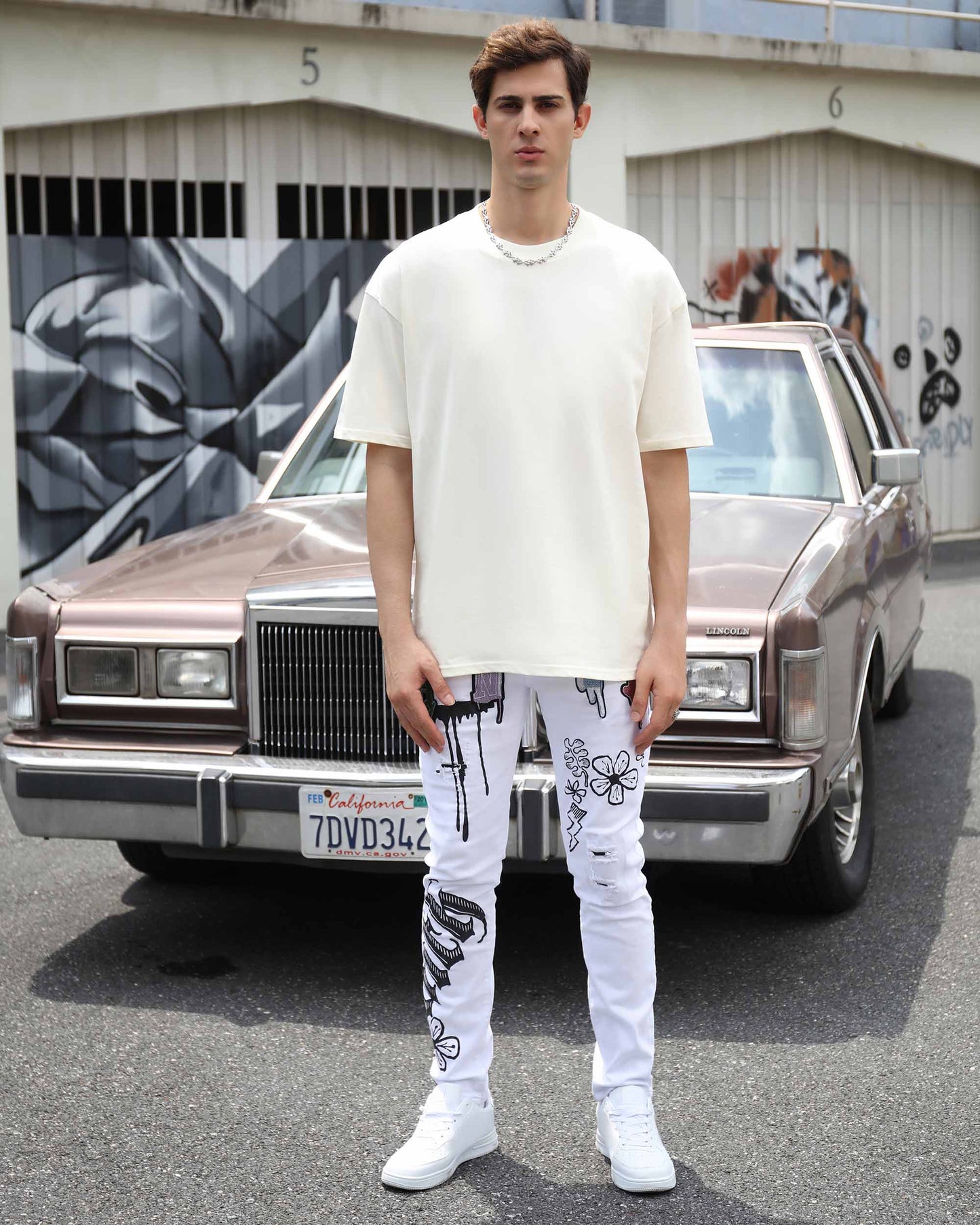 Logeqi streetwear graffiti jeans in white with unique black print, styled with a casual top and sneakers