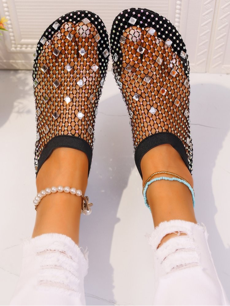Stylish solid color sandals with black mesh and rhinestone details worn with white ripped jeans
