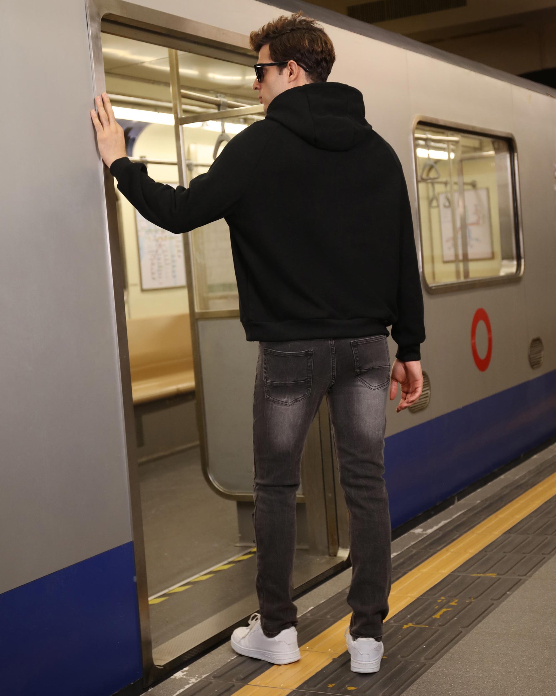 Man wearing Logeqi stylish straight leg jeans in black walking into a subway train