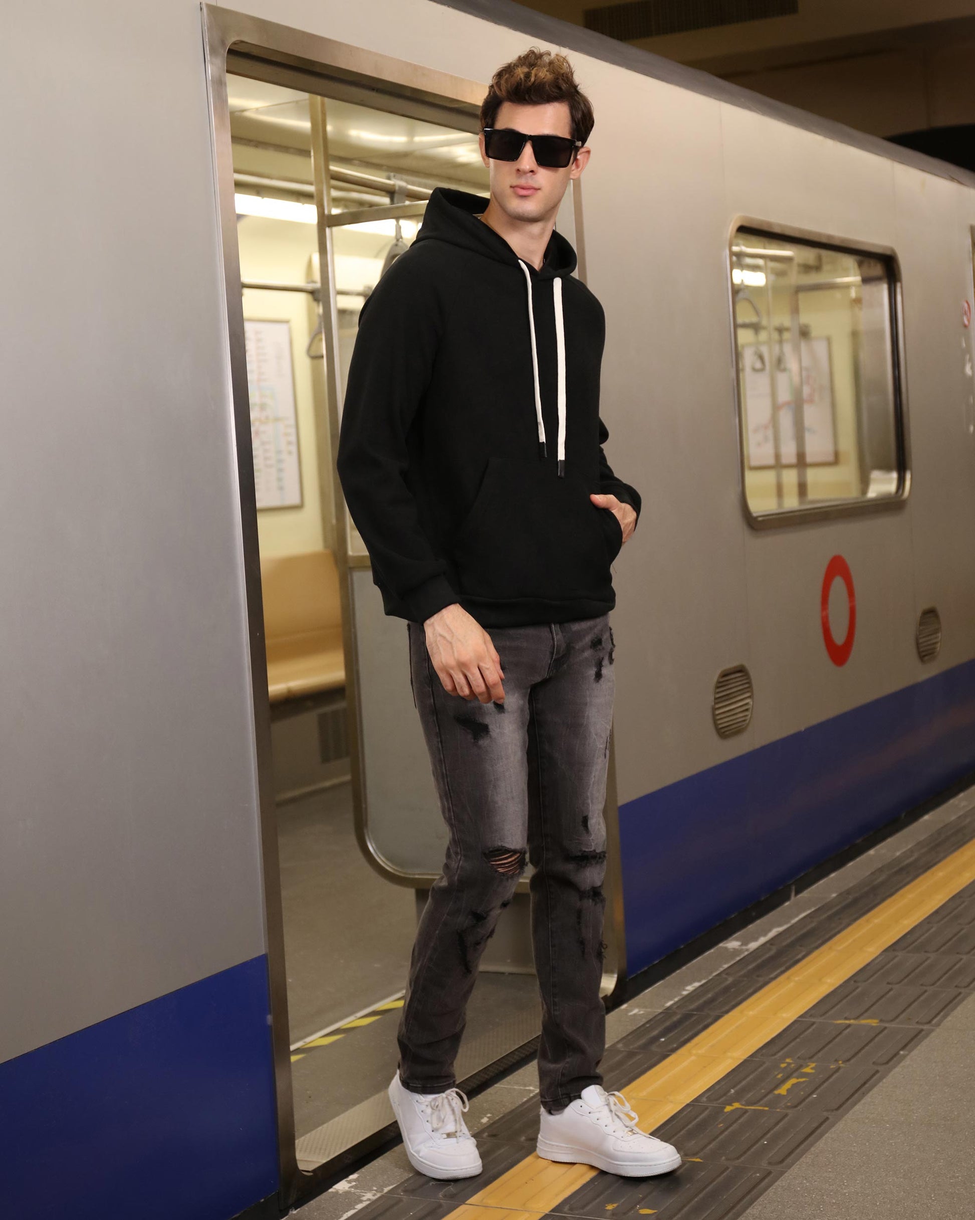 Logeqi stylish straight leg jeans worn by a man with black hoodie and white sneakers at subway station