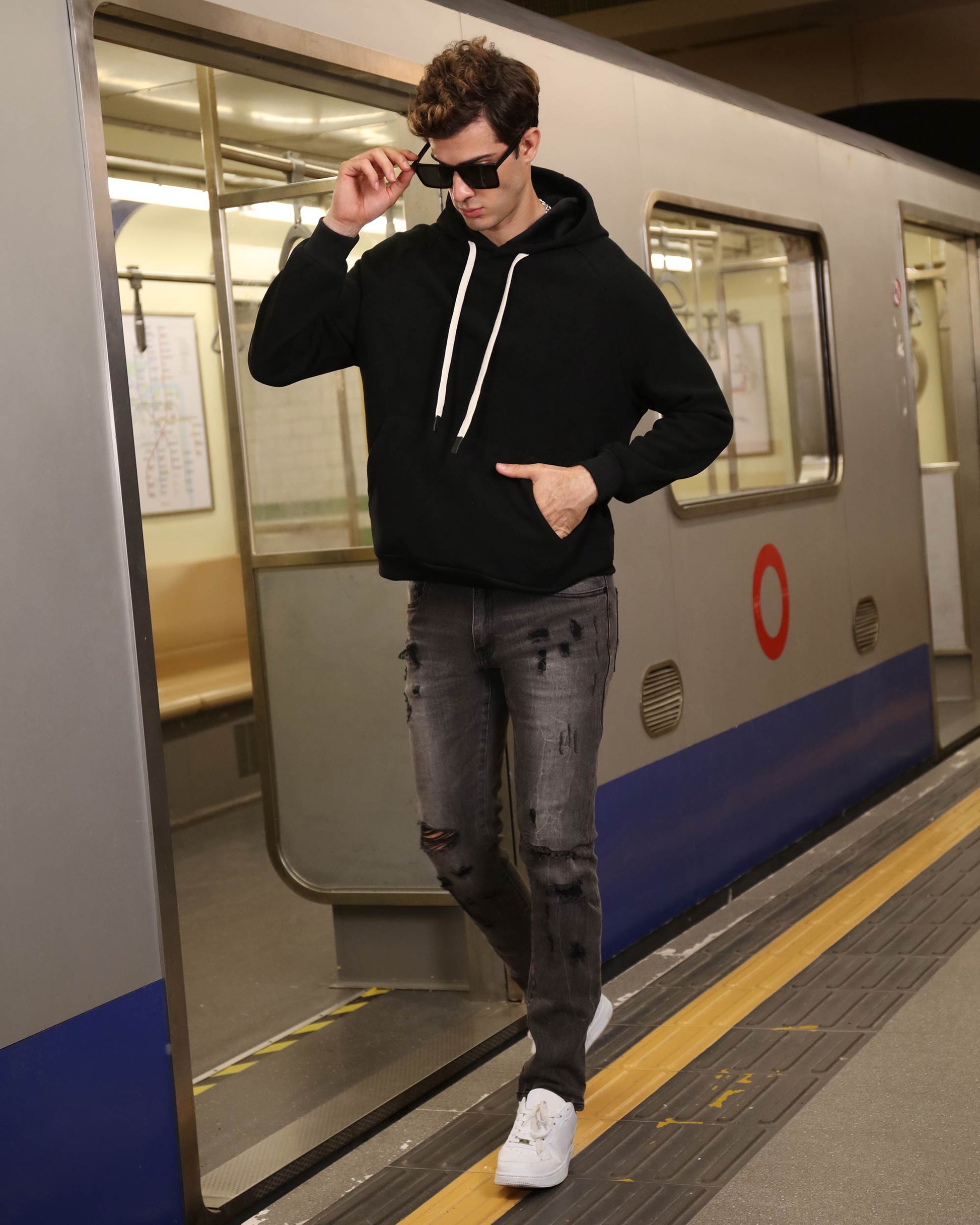 Logeqi stylish straight leg jeans in black with distressed details worn by man exiting subway train