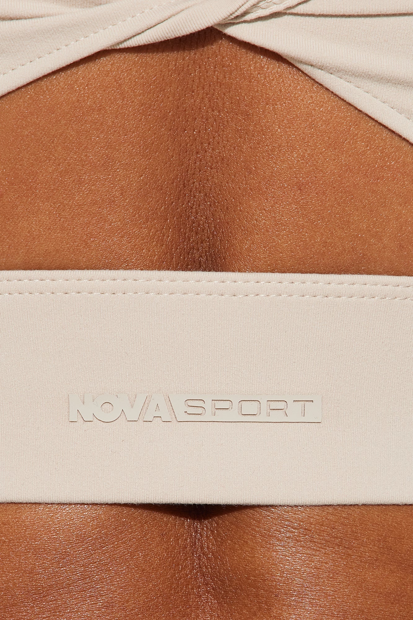 Close-up of Nova Sport logo on nude super soft active top designed for comfort and style
