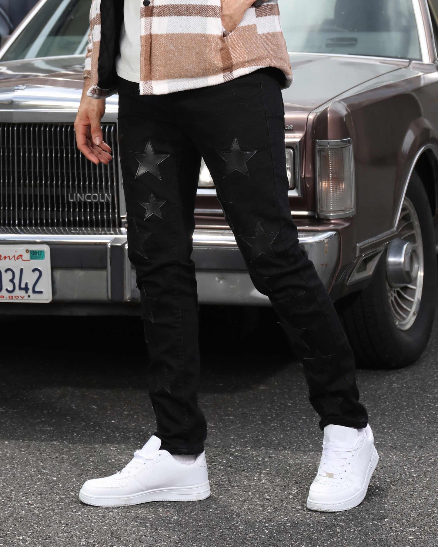 Logeqi black straight leg jeans with star patches worn with white sneakers and plaid jacket