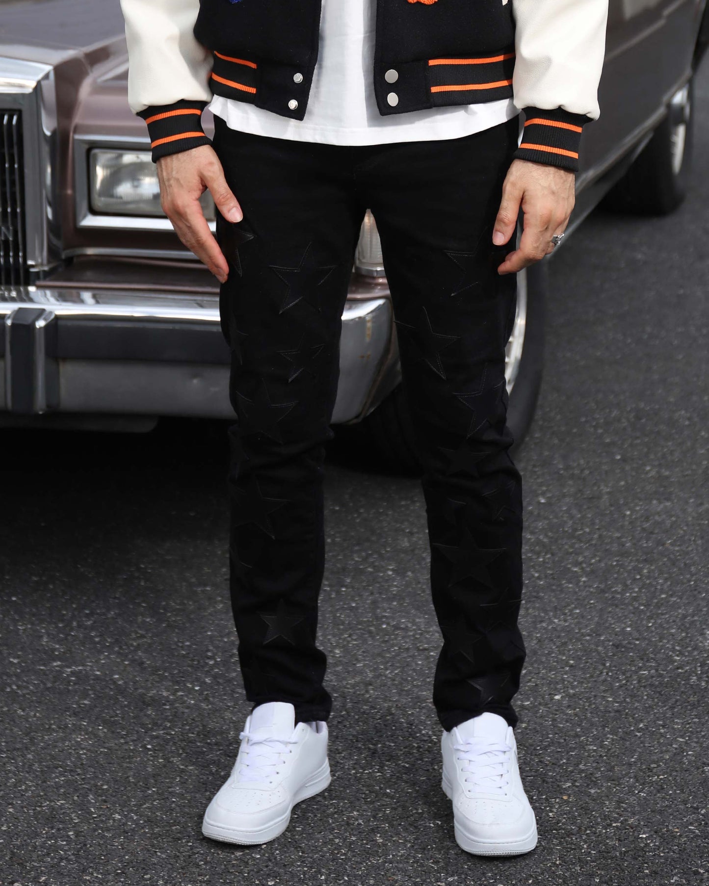 Logeqi black straight leg jeans worn with white sneakers and a varsity jacket on street