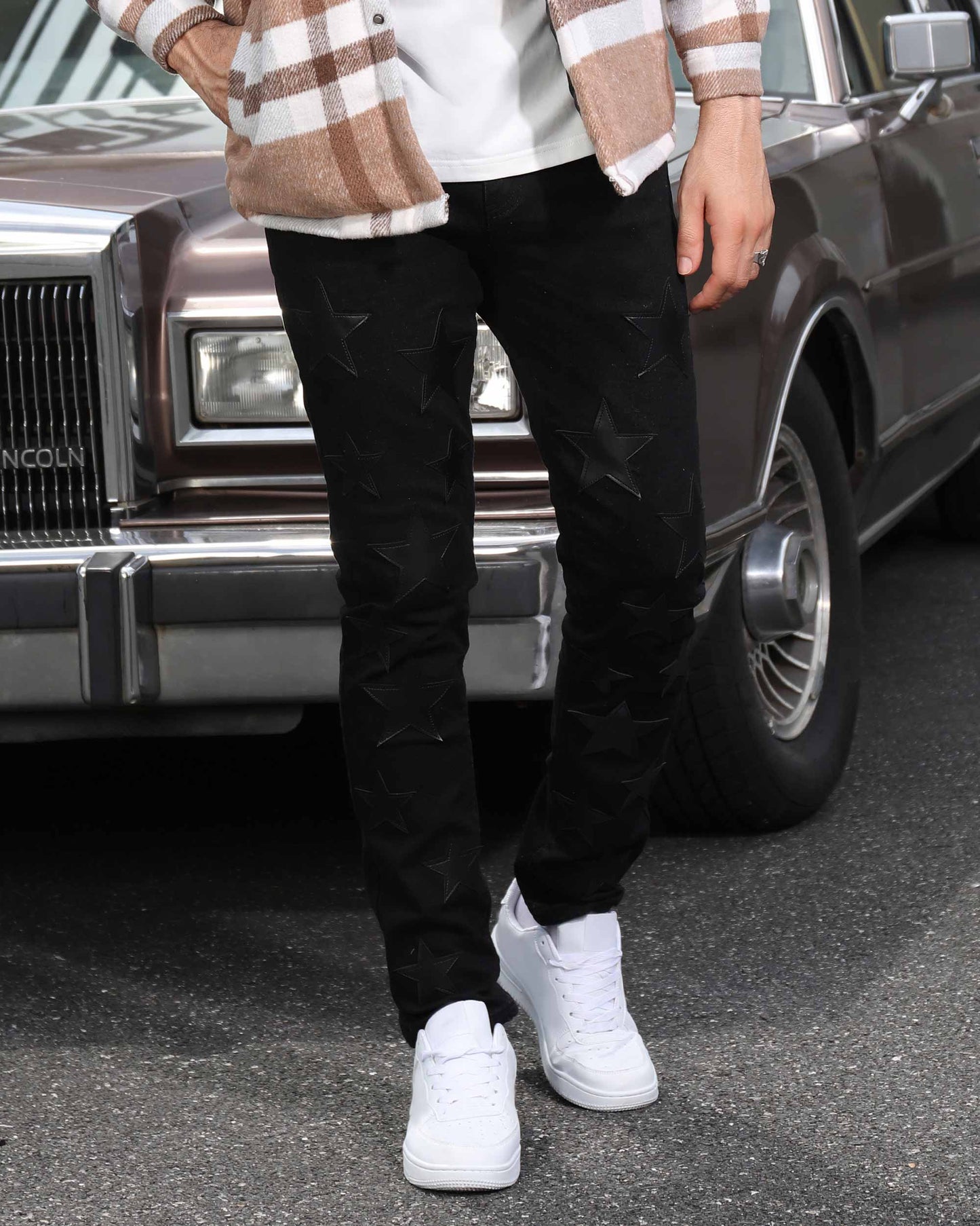 Logeqi black straight leg jeans with star pattern worn with white sneakers and plaid shirt