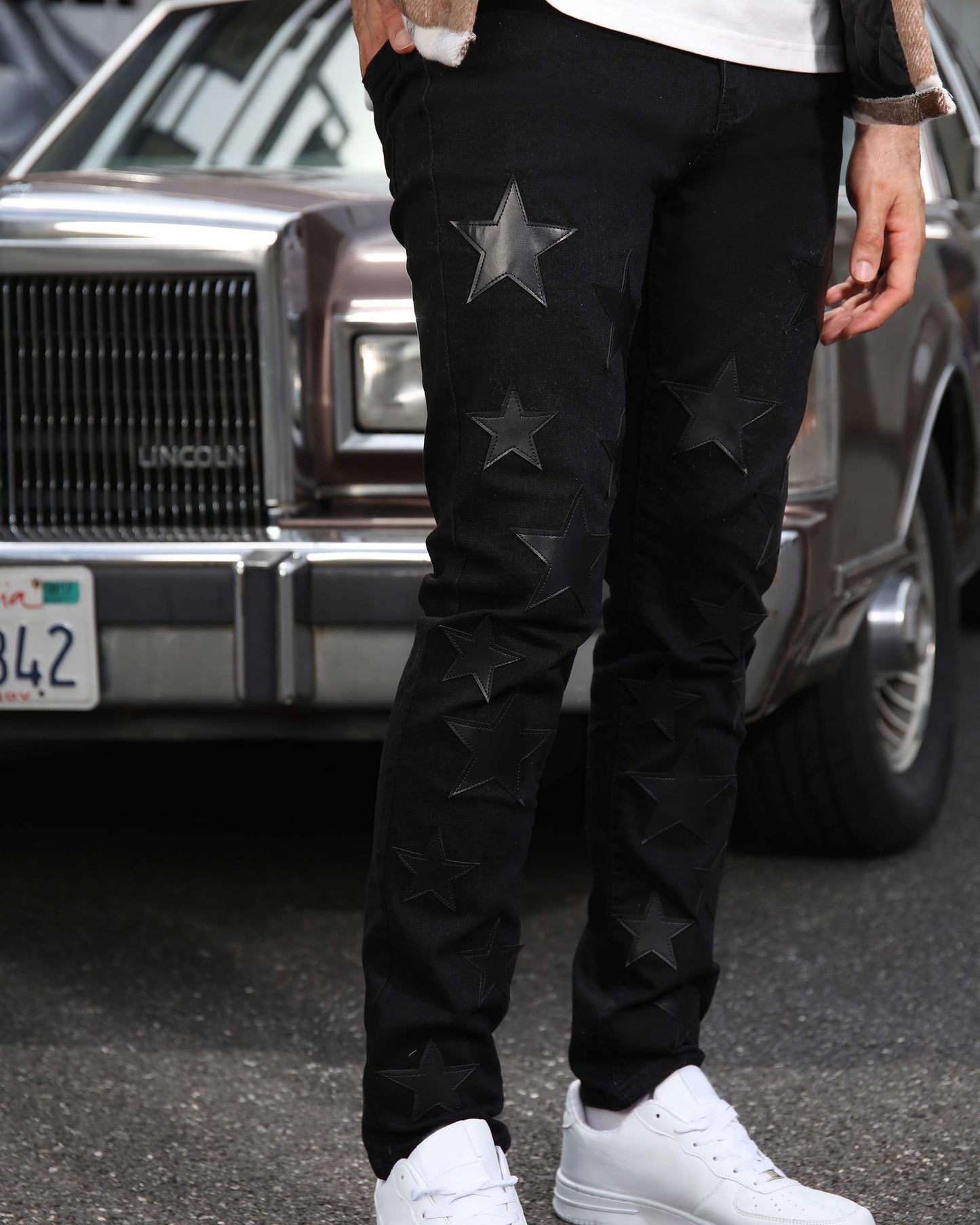 Logeqi black straight leg jeans with star patterns worn with white sneakers in urban setting