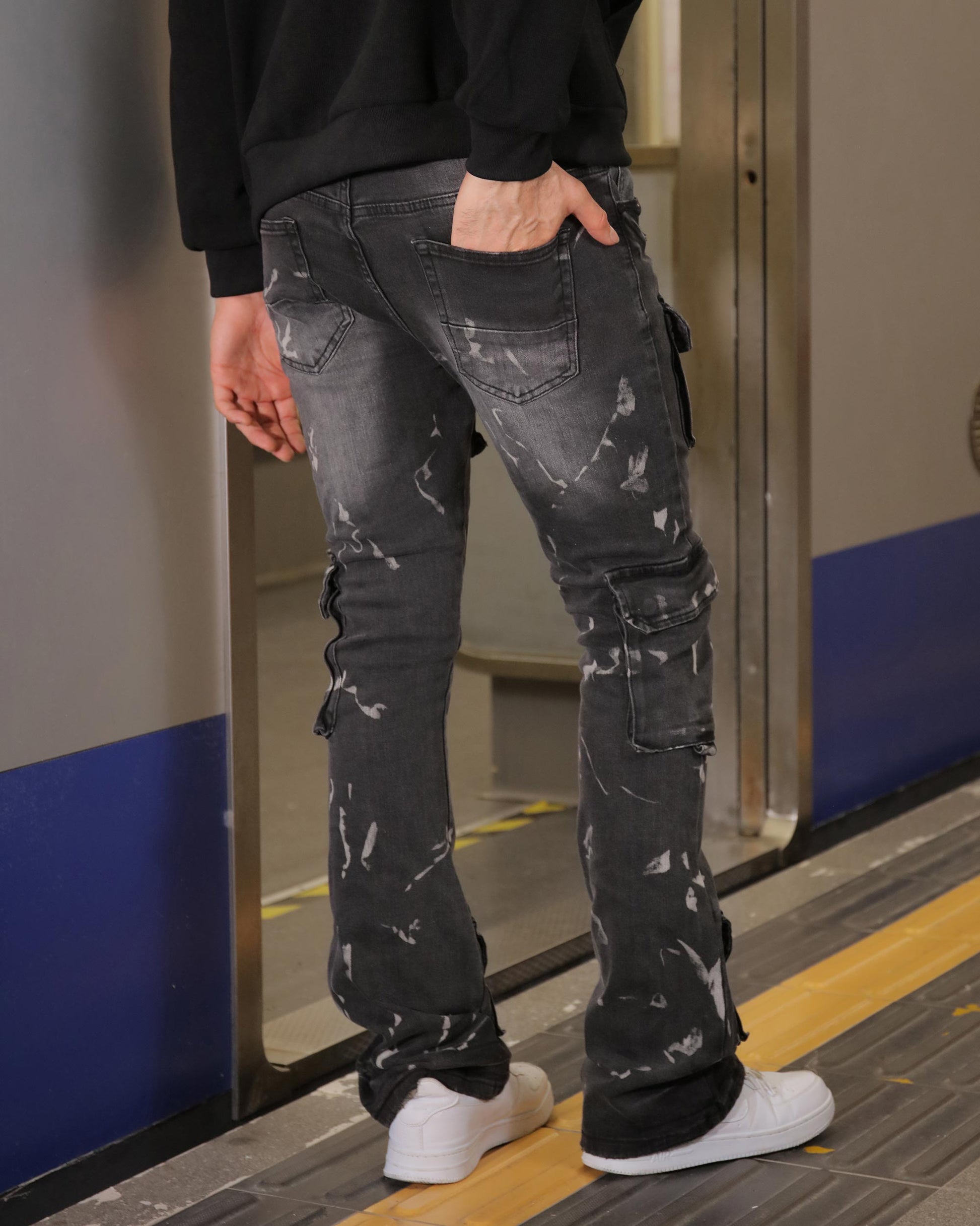 Logeqi distressed black cargo jeans worn by a man with white sneakers standing indoors