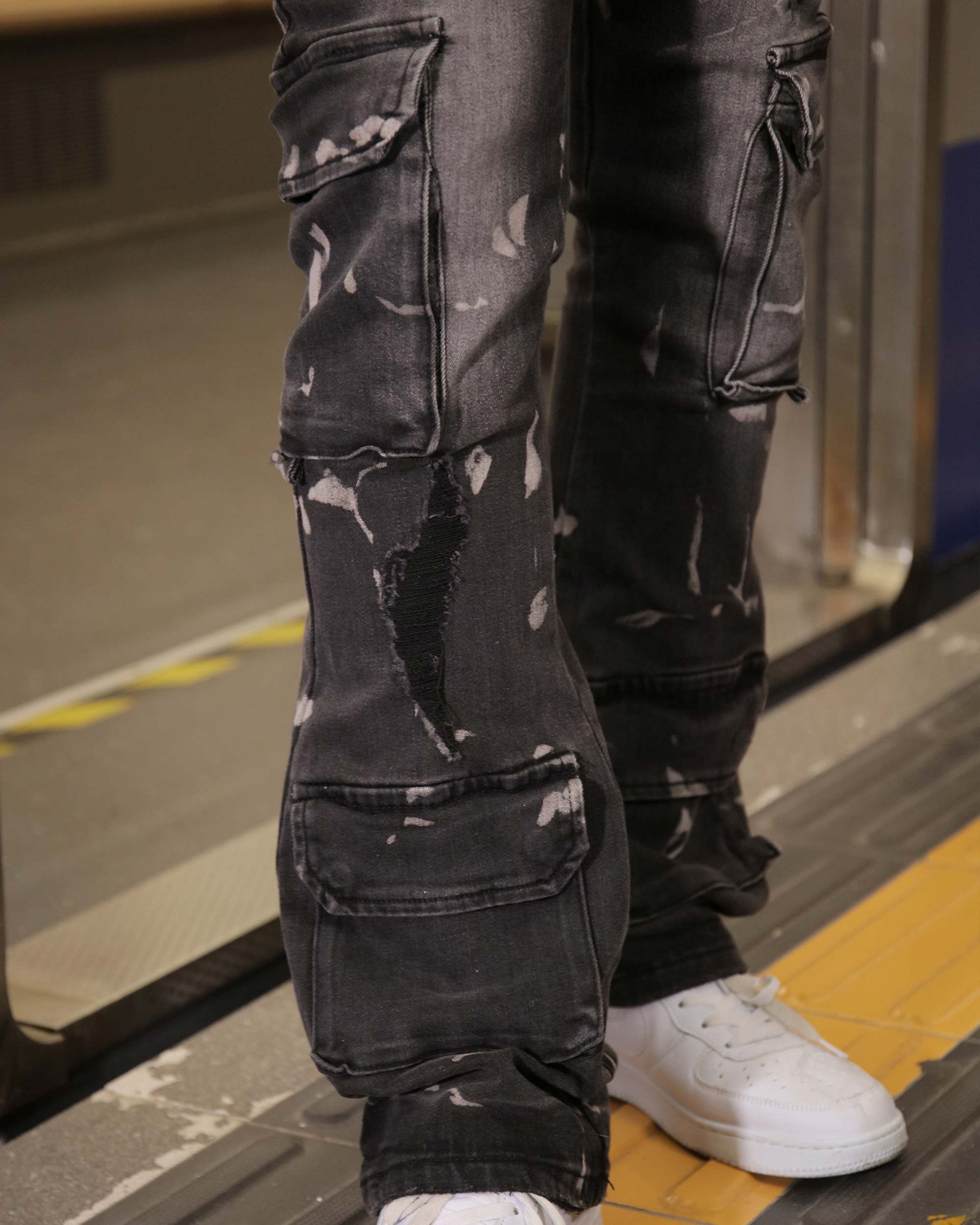 Close-up of Logeqi distressed black cargo jeans with multiple pockets and white sneakers