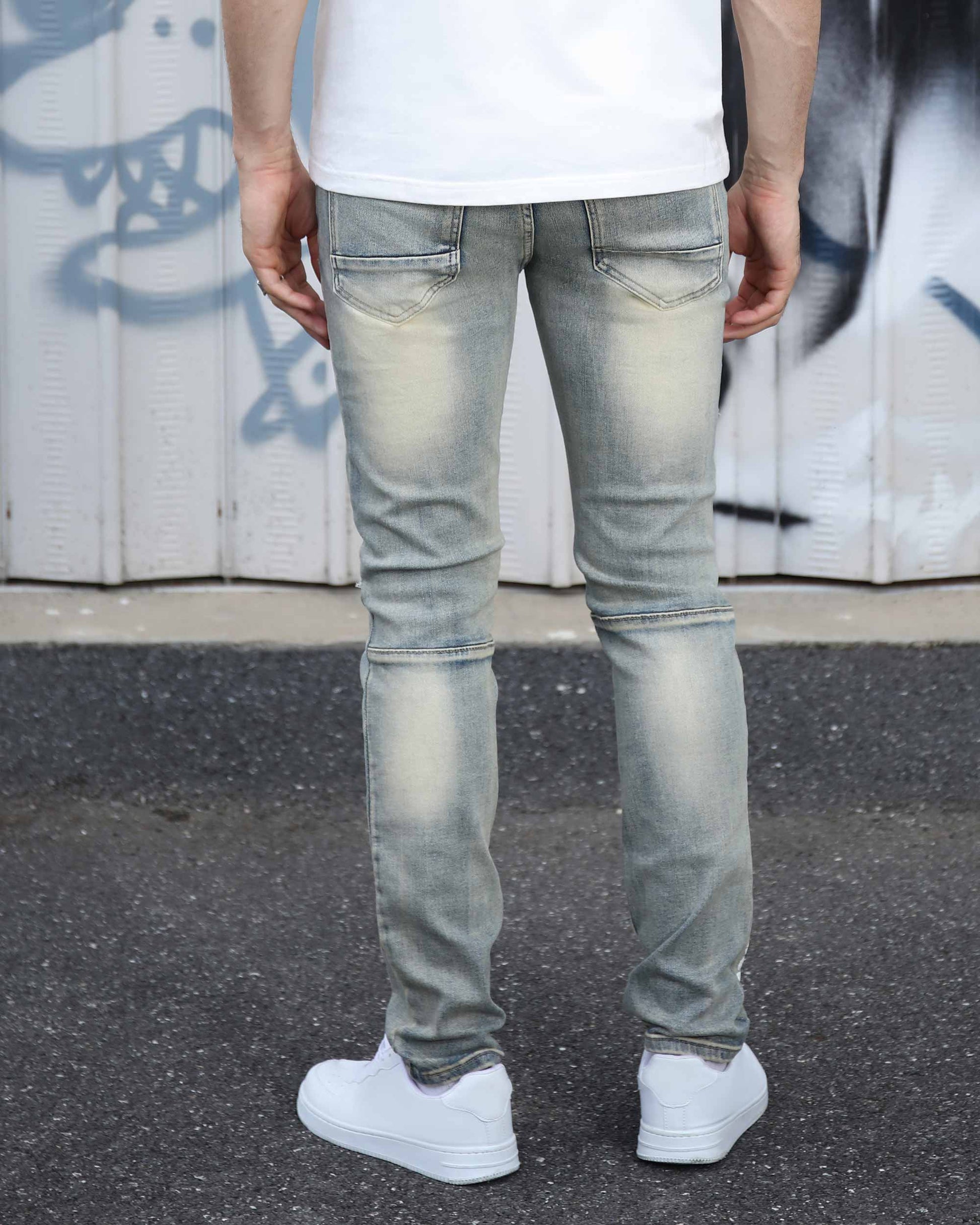 Logeqi distressed light wash jeans shown from the back on a male model wearing white sneakers